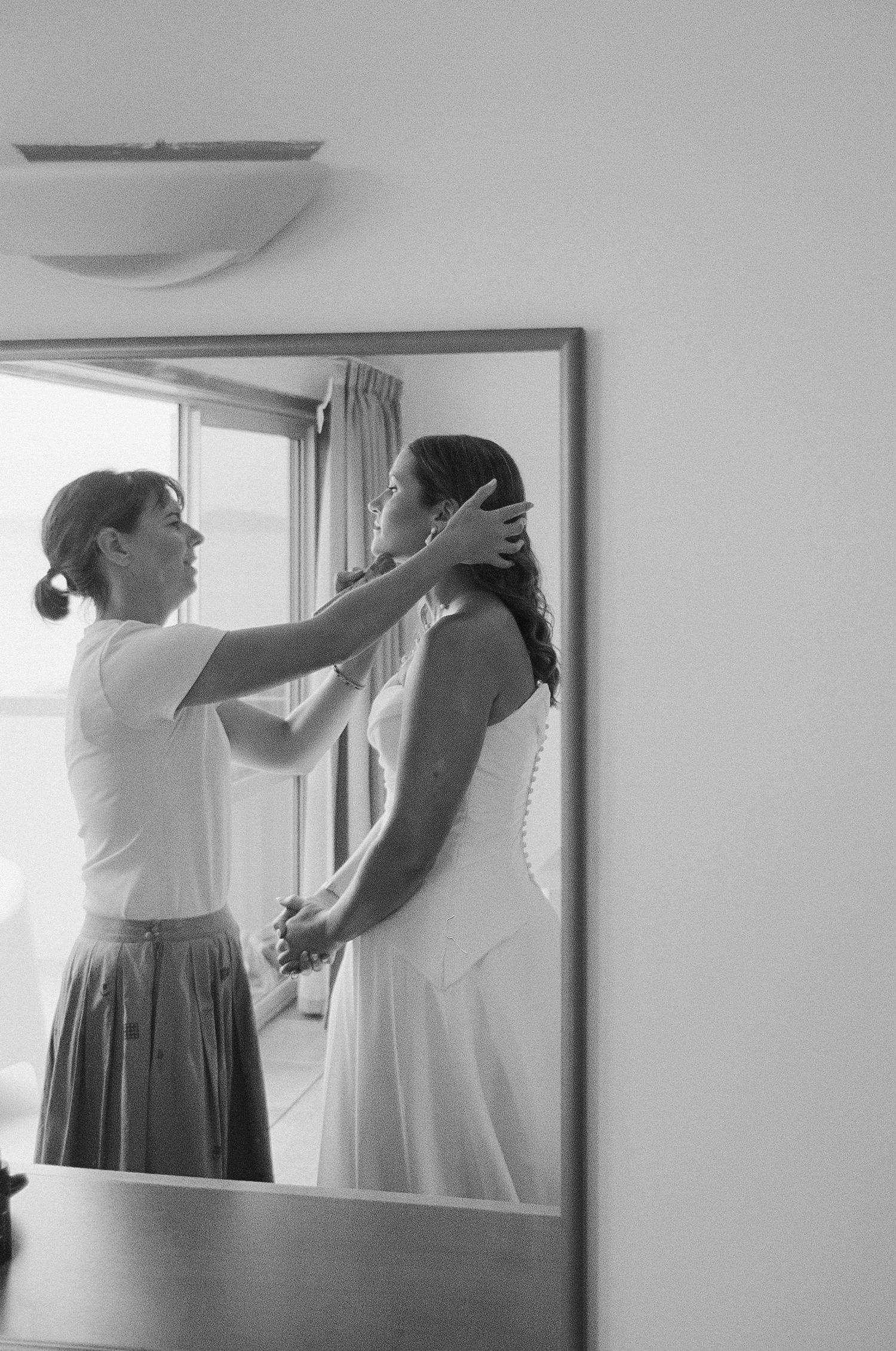 Black and white series showing a person helping another with dress adjustments and measurements in a fitting room.