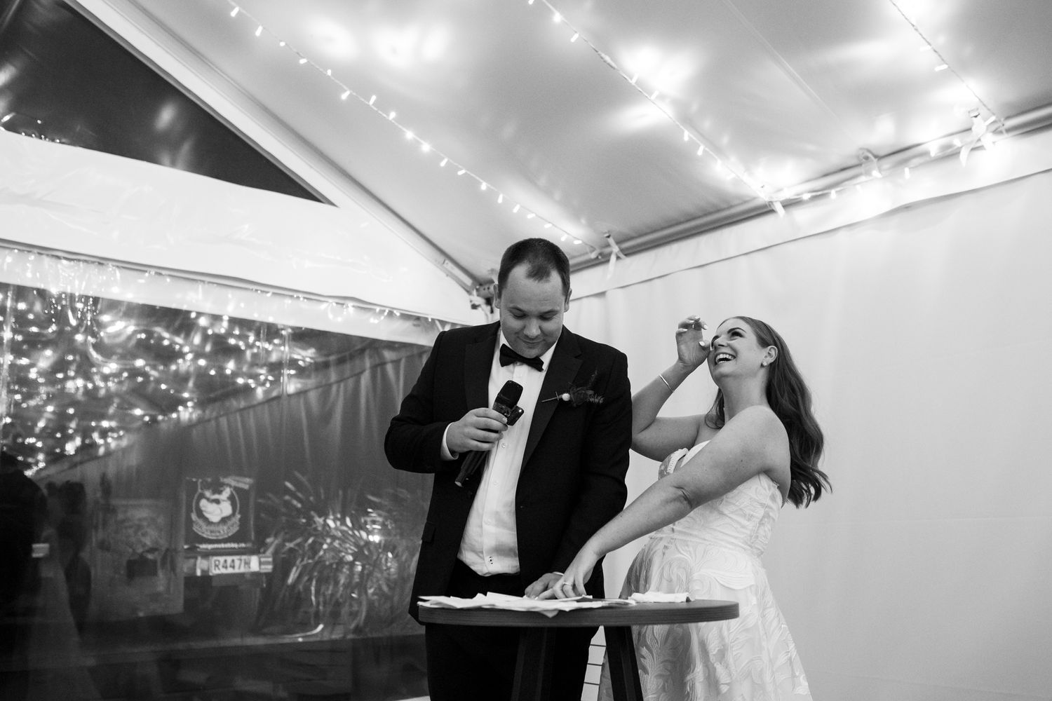 Wedding reception scene with string lights overhead as couple shares a celebratory moment.