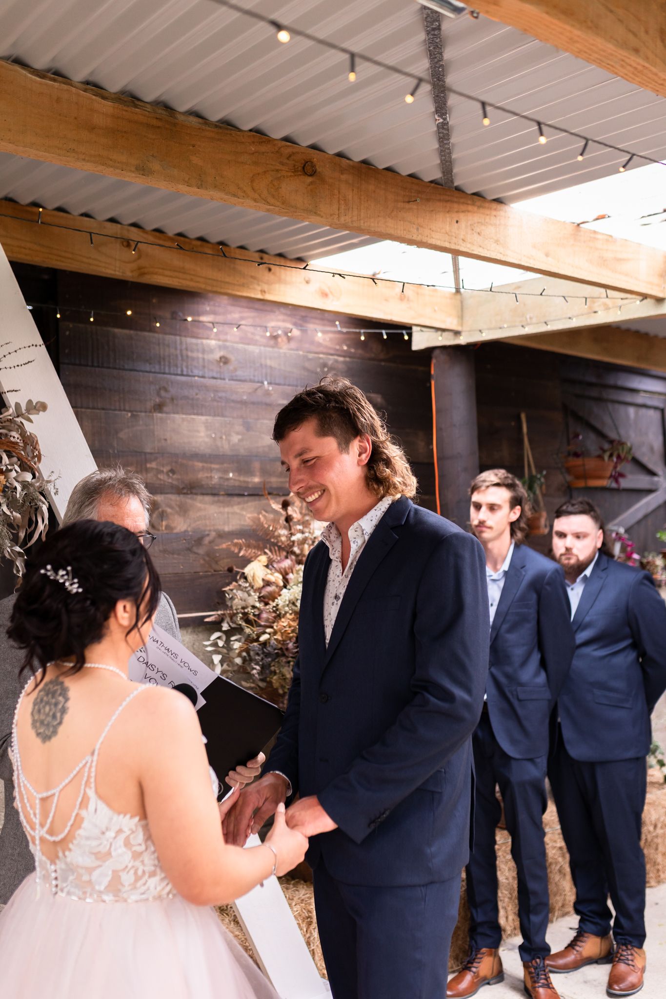 Wedding ceremony in a rustic venue with wooden walls and string lights overhead.
