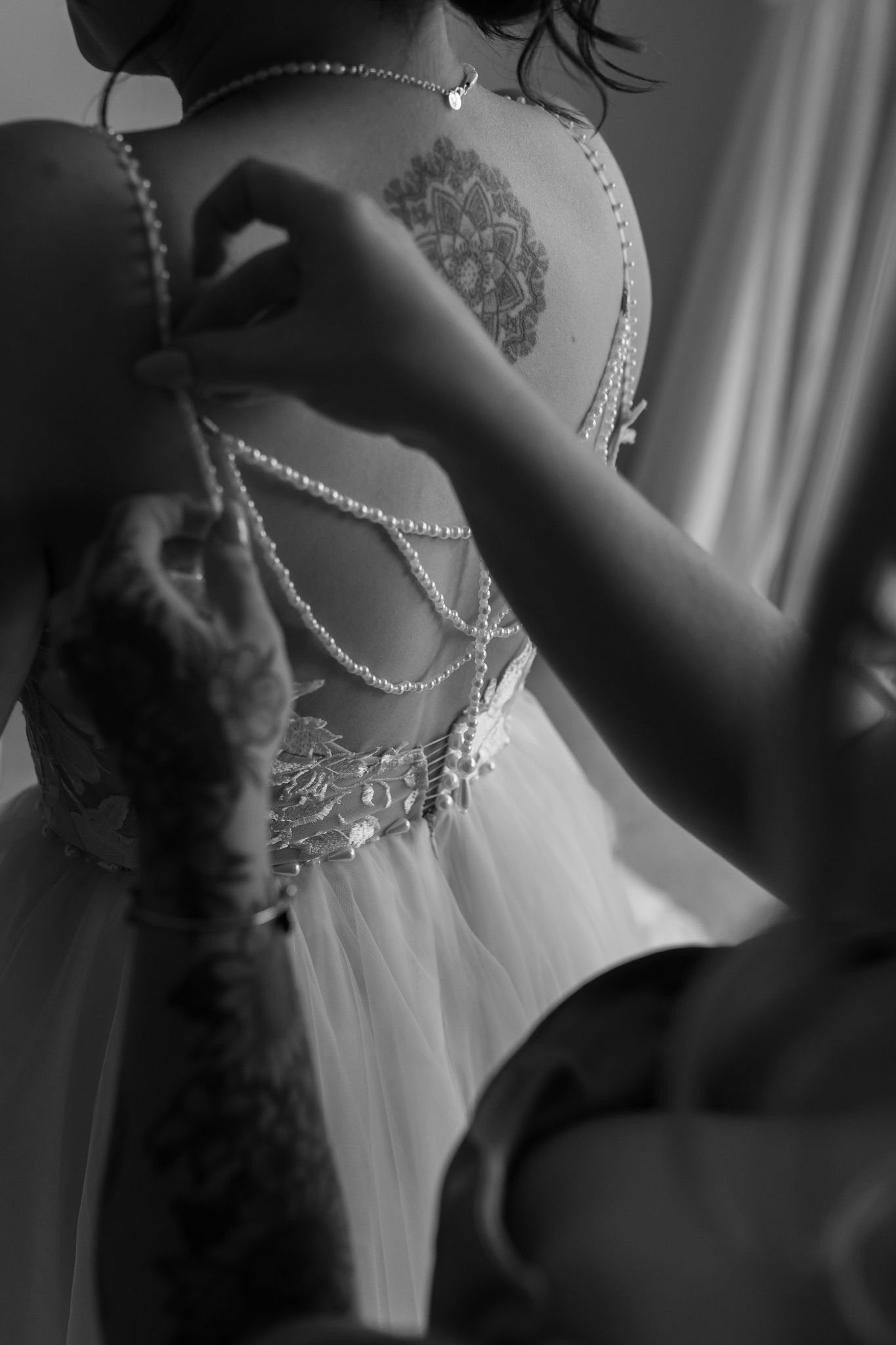Close-up detail of an intricate lace wedding dress back with delicate pearl strands.