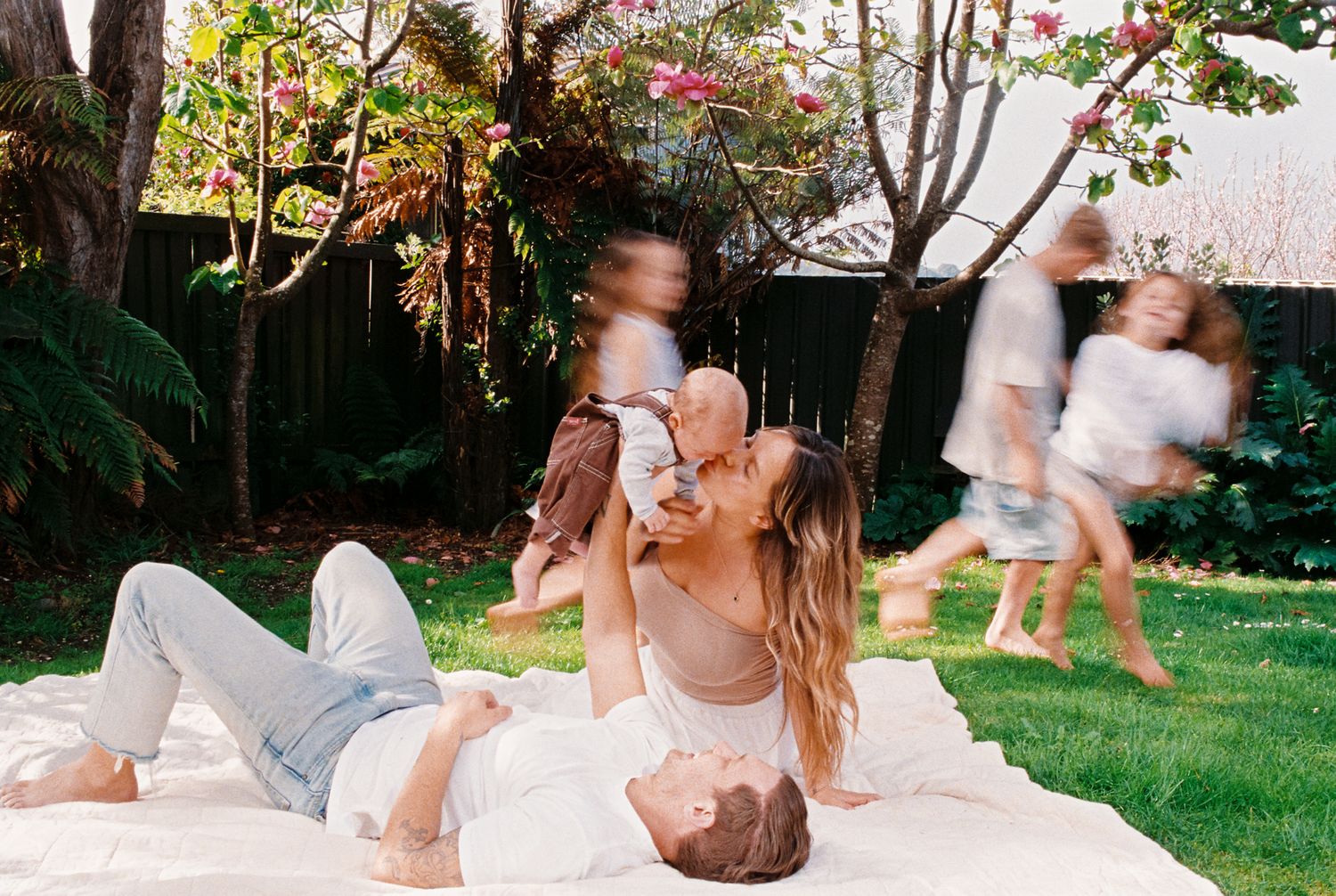 Sequence of black and white images showing a baby rolling and playing on grass in a backyard setting.
