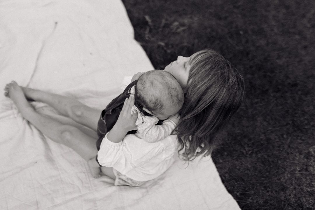 A young child rests peacefully on a white blanket in black and white photography. Authentic family film photography