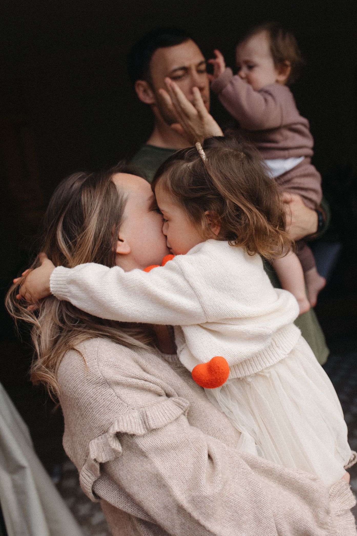A tender embrace between parent and child wearing matching cream-colored knit sweaters with a pop of orange.