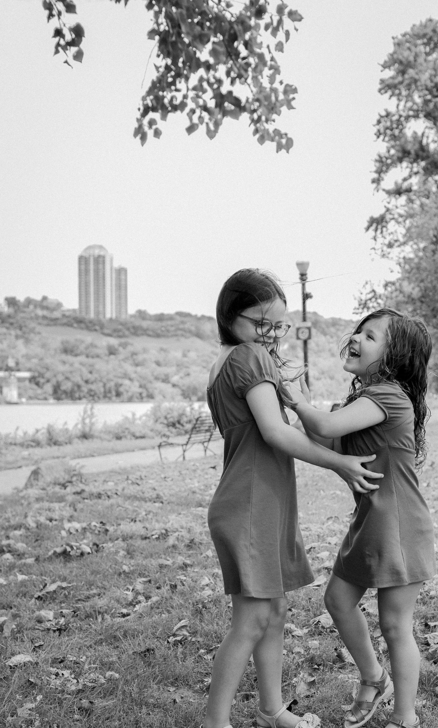 Two girls laughing in a black and white outdoor park photo.