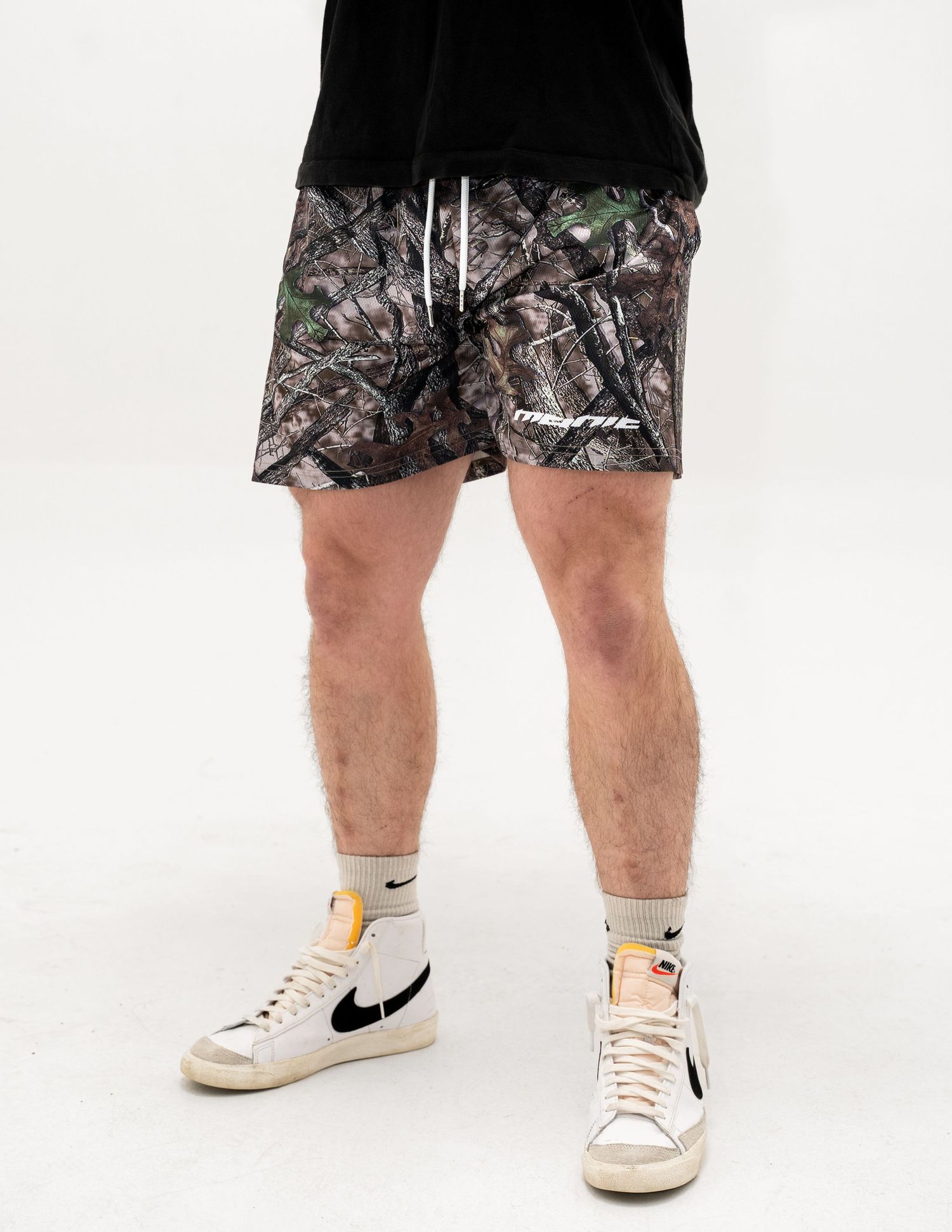 Camouflage pattern shorts paired with white Nike Blazer high-top sneakers.