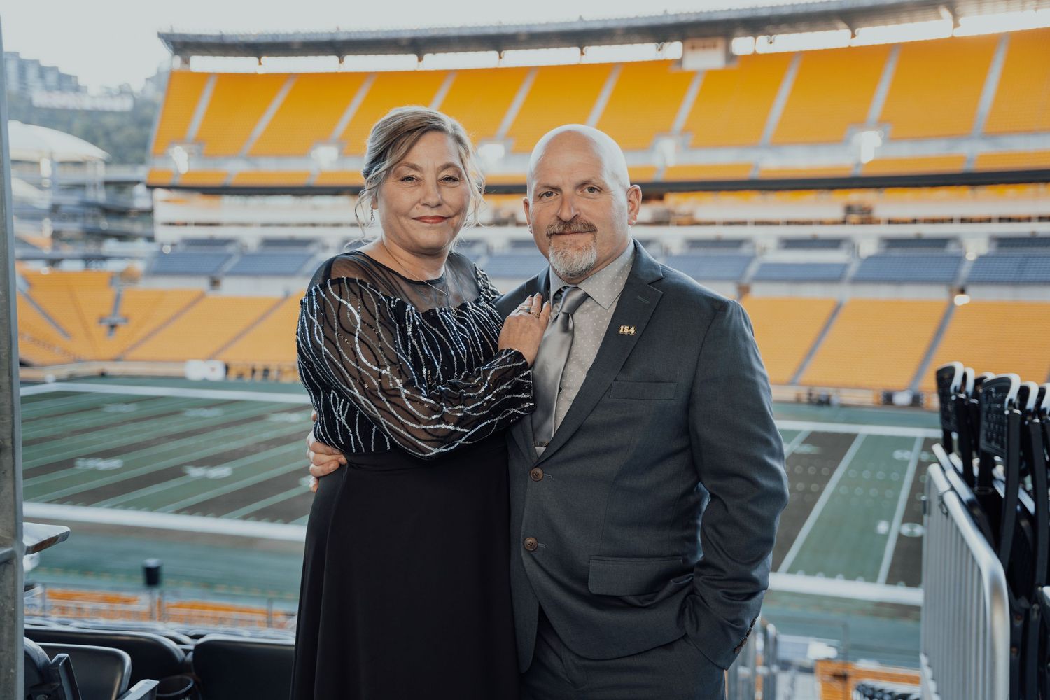 A couple poses for a photo with Heinz Field stadium in the background.