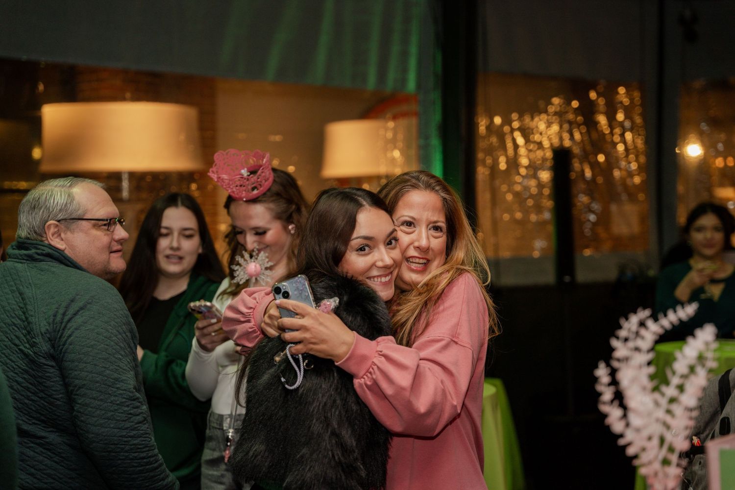 People dancing and celebrating at an indoor event with warm lighting and festive decorations.