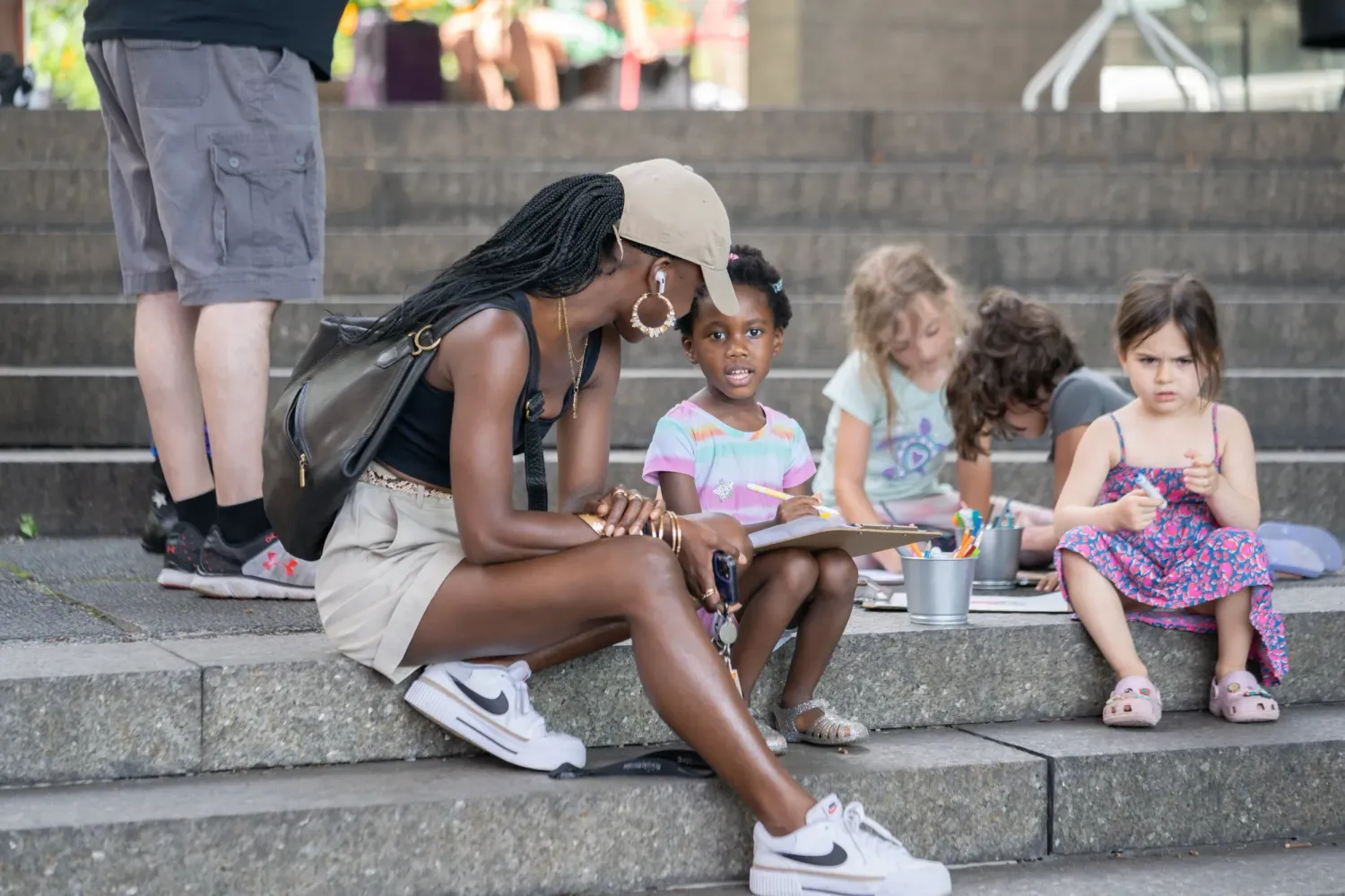 People sitting in a row on large concrete steps while chatting and spending time together outdoors.