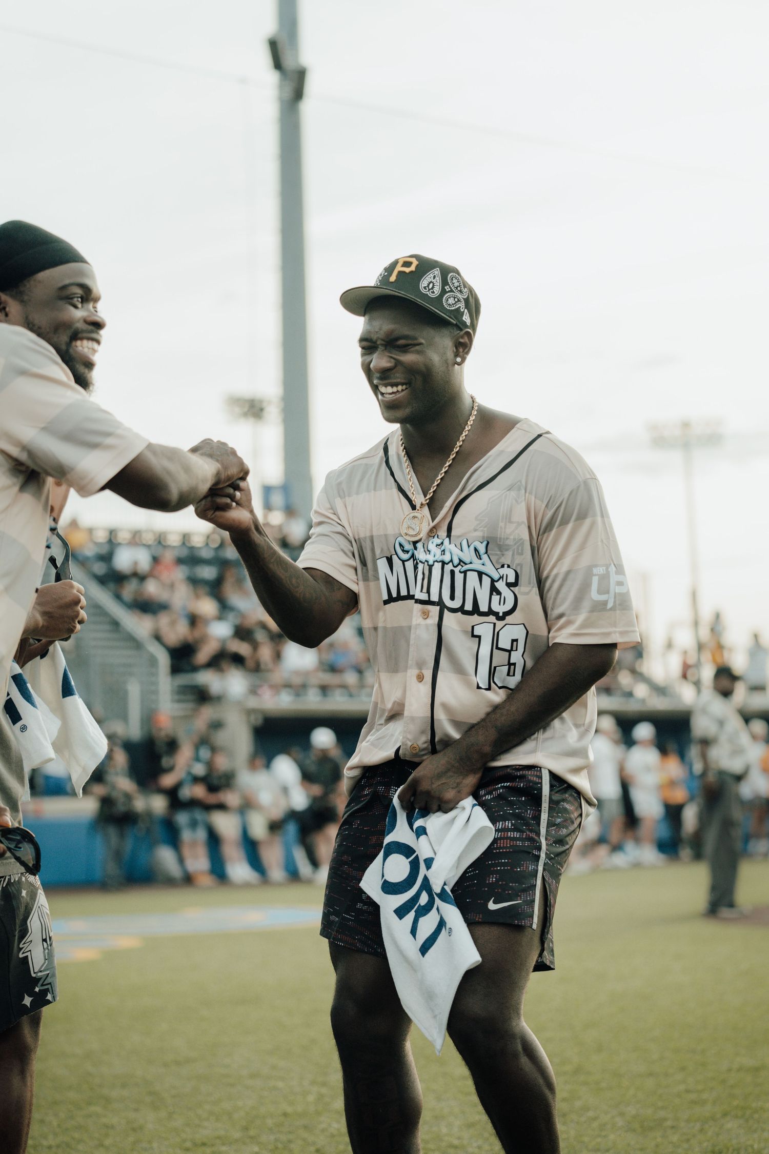 Athletes share a celebratory handshake on a sports field while wearing baseball jerseys during a game.