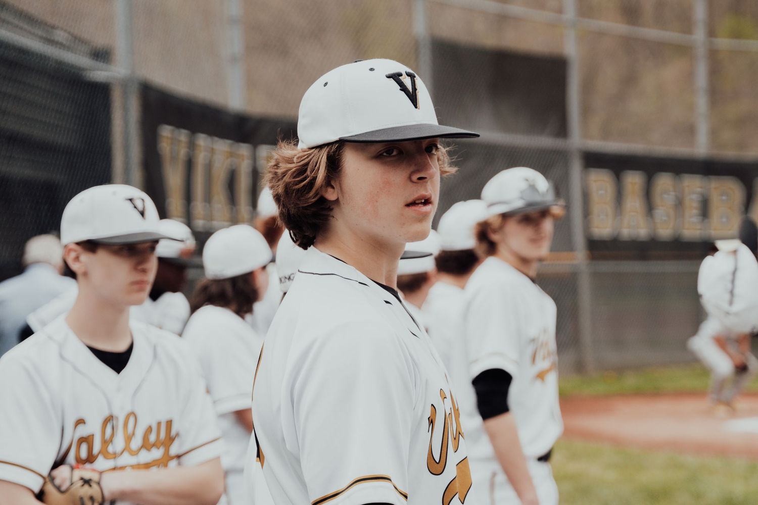 Baseball player in white uniform pitches from the mound during a game at Valley Vikings field.