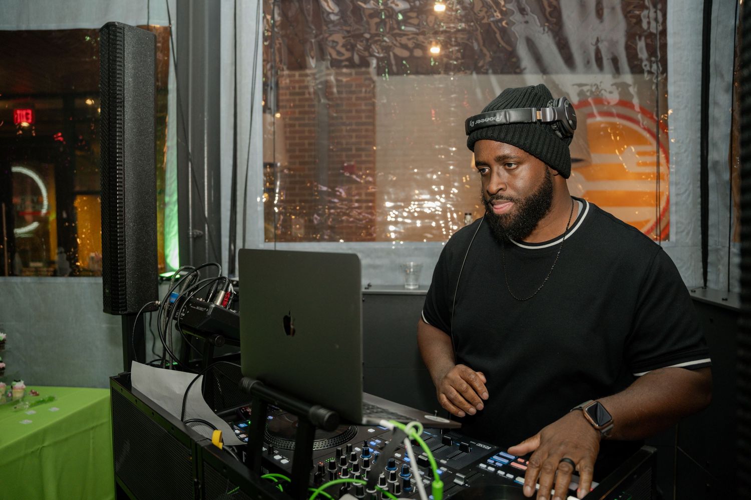 DJ performing at an event setup with professional equipment and dim atmospheric lighting.