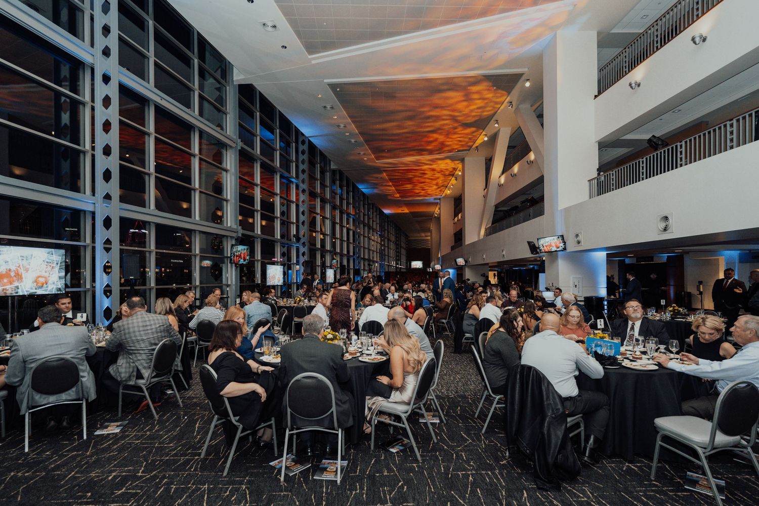 A large banquet hall filled with round tables and guests during an evening event.