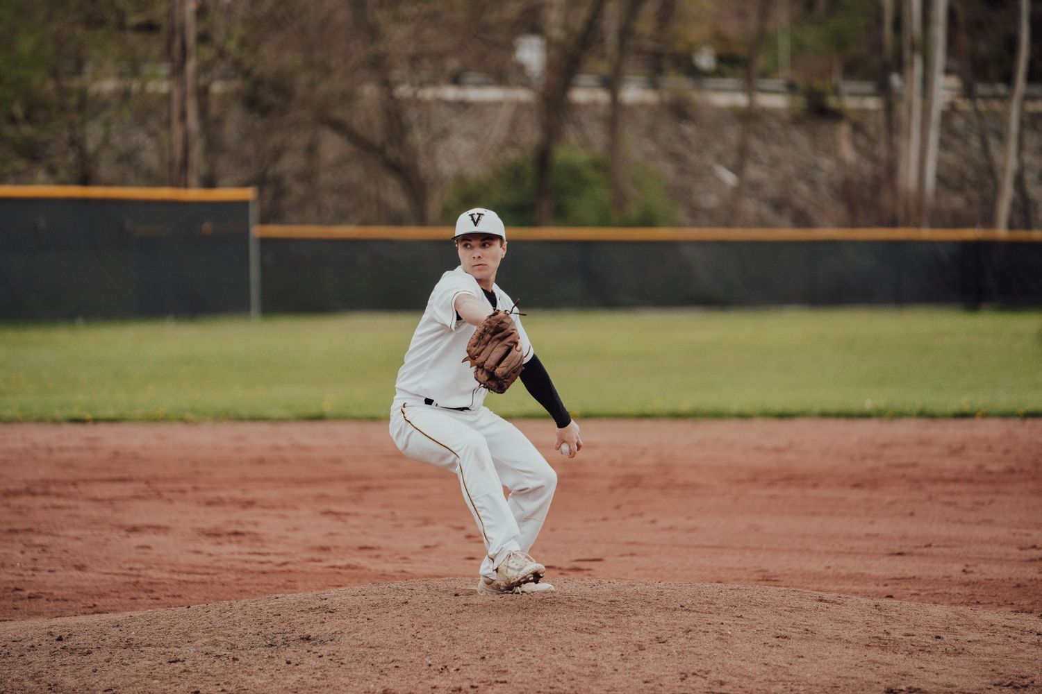 Baseball player fields ground ball on dirt infield during practice session.