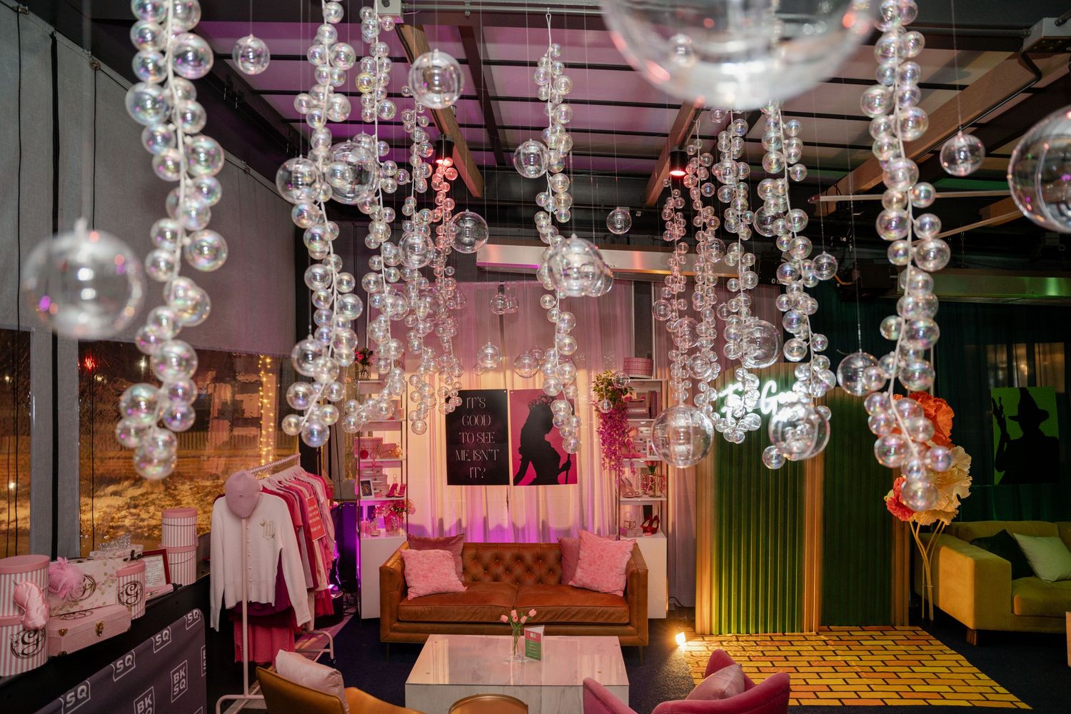 Trendy lounge space with hanging bubble chandeliers, pink lighting, and modern seating arrangements in an intimate setting.
