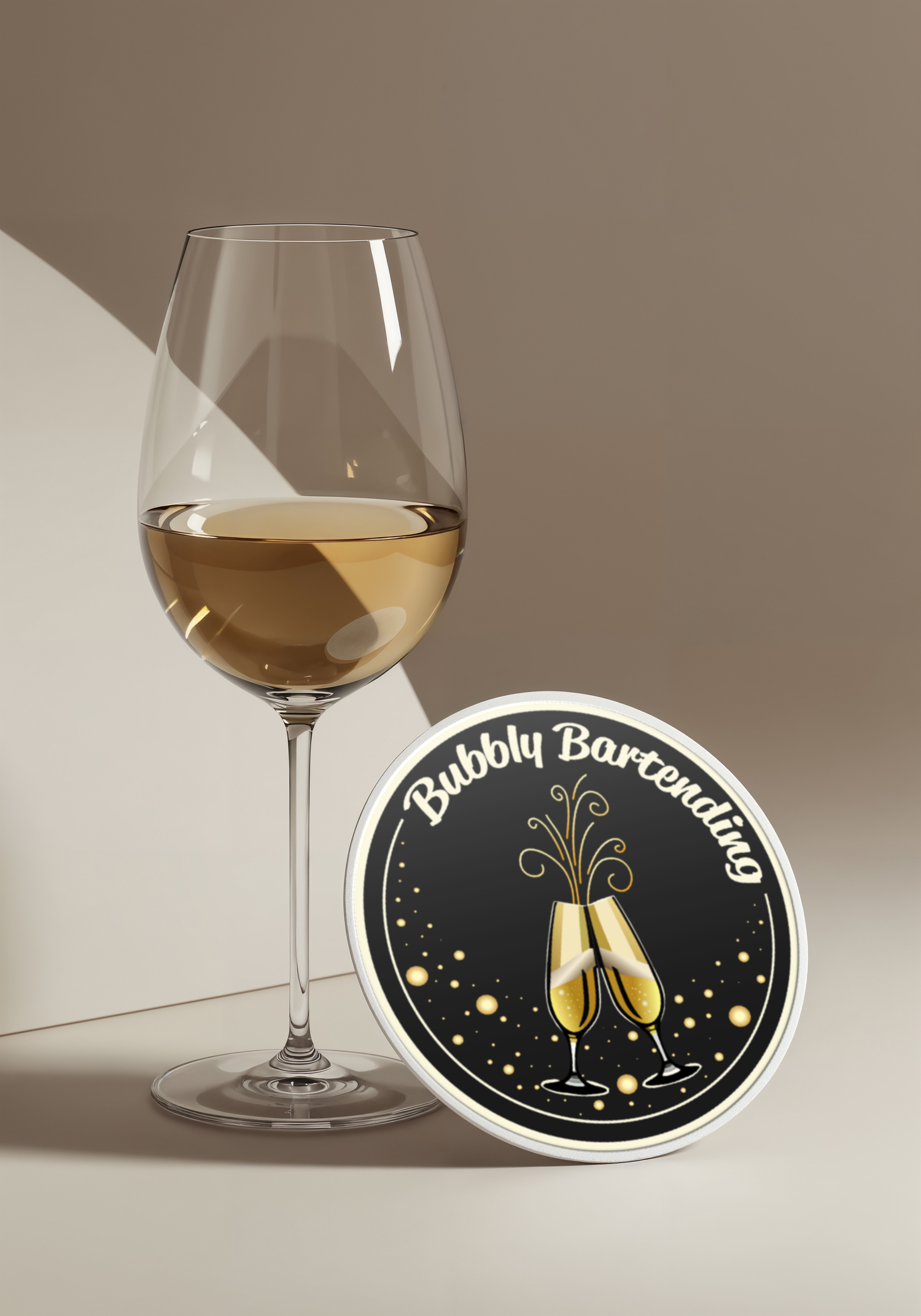 A glass of white wine stands beside a black coaster with gold champagne flute design and 'Bubbly Bartending' text.
