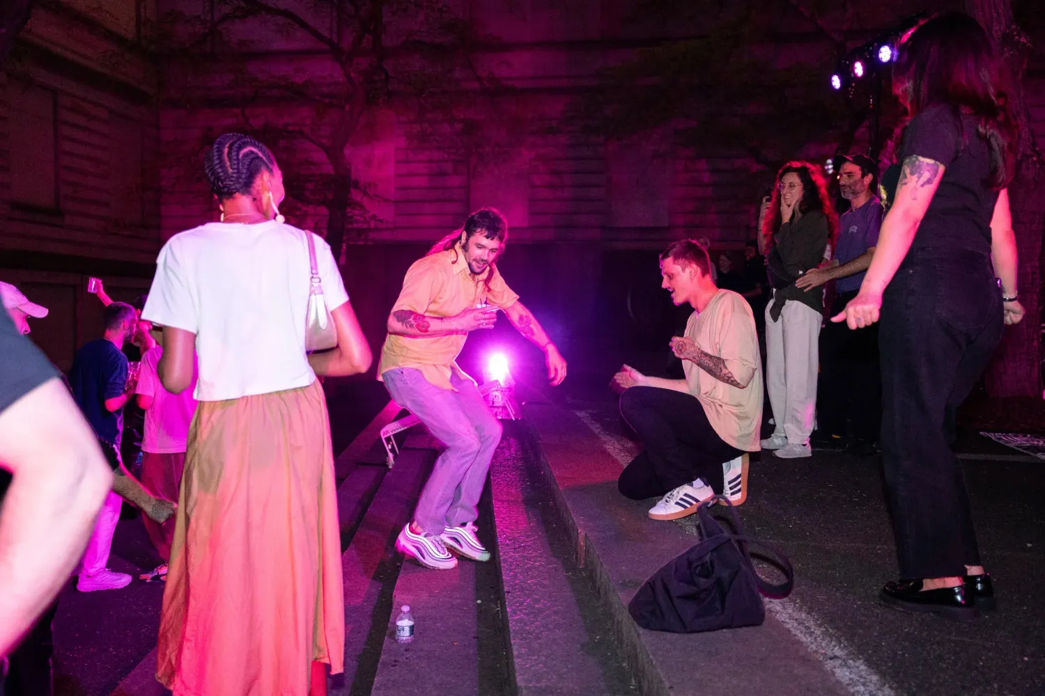 People dancing in a dark venue illuminated by purple lights and glowing objects while music plays.