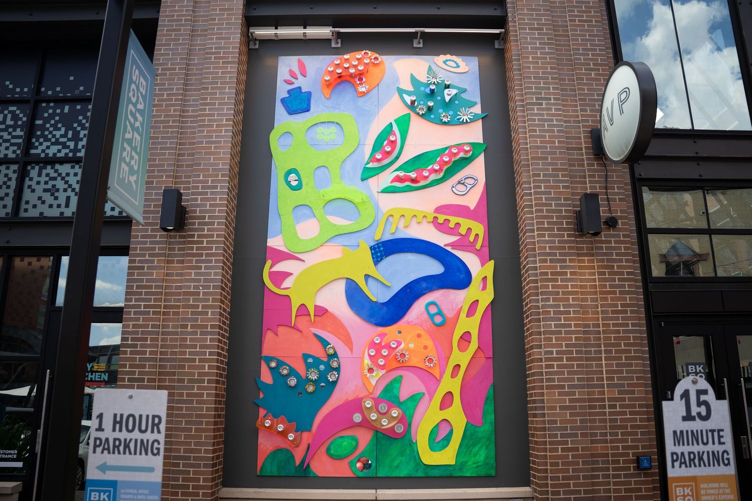 Colorful abstract mural featuring organic shapes and patterns displayed on a brick building exterior.