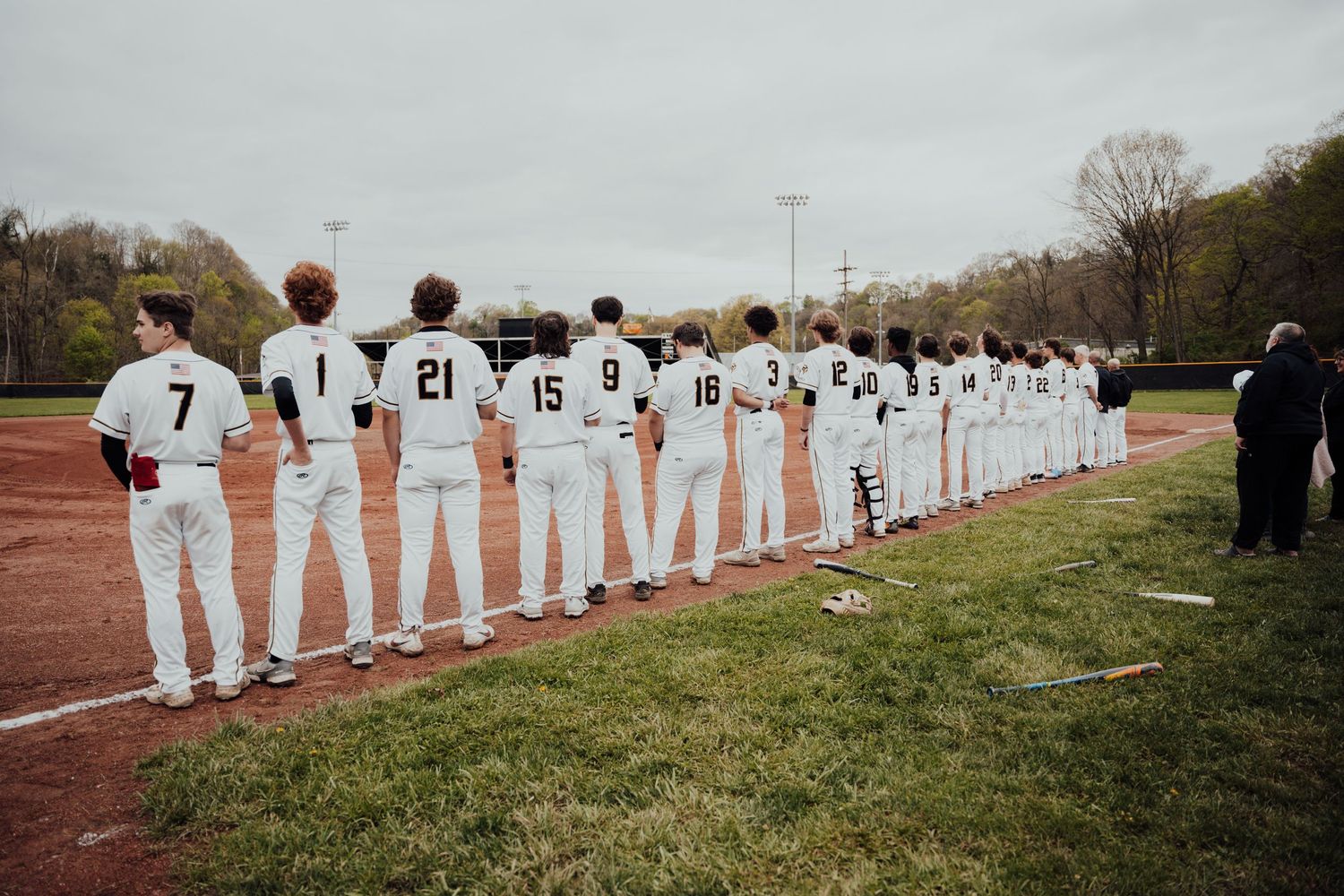 Baseball team members lined up along a fence during a game or practice session.