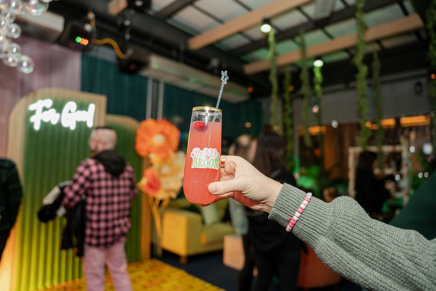 Colorful illuminated indoor venue with exposed ceiling beams features neon green and pink lighting creating an atmospheric ambiance.