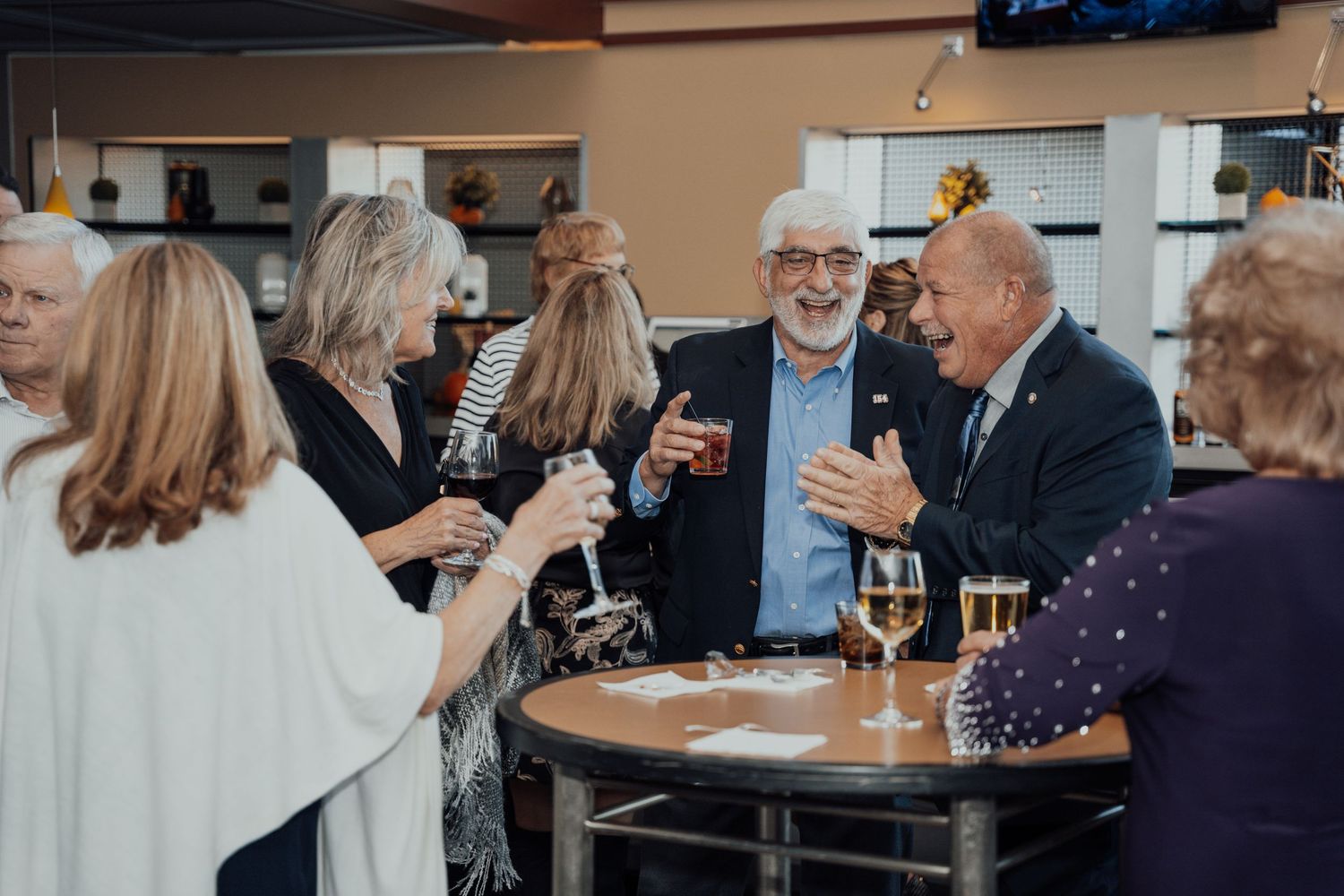 People gather at tables in an elegant restaurant setting with wine glasses and formal attire.