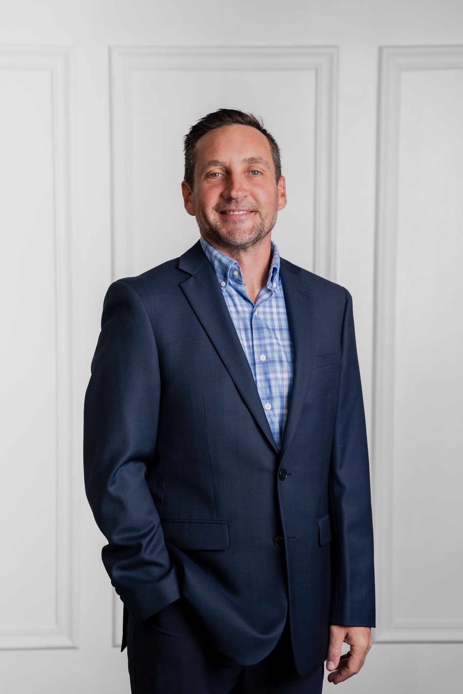Professional business portrait series showing a person in a navy suit and blue checkered dress shirt against a white backdrop.