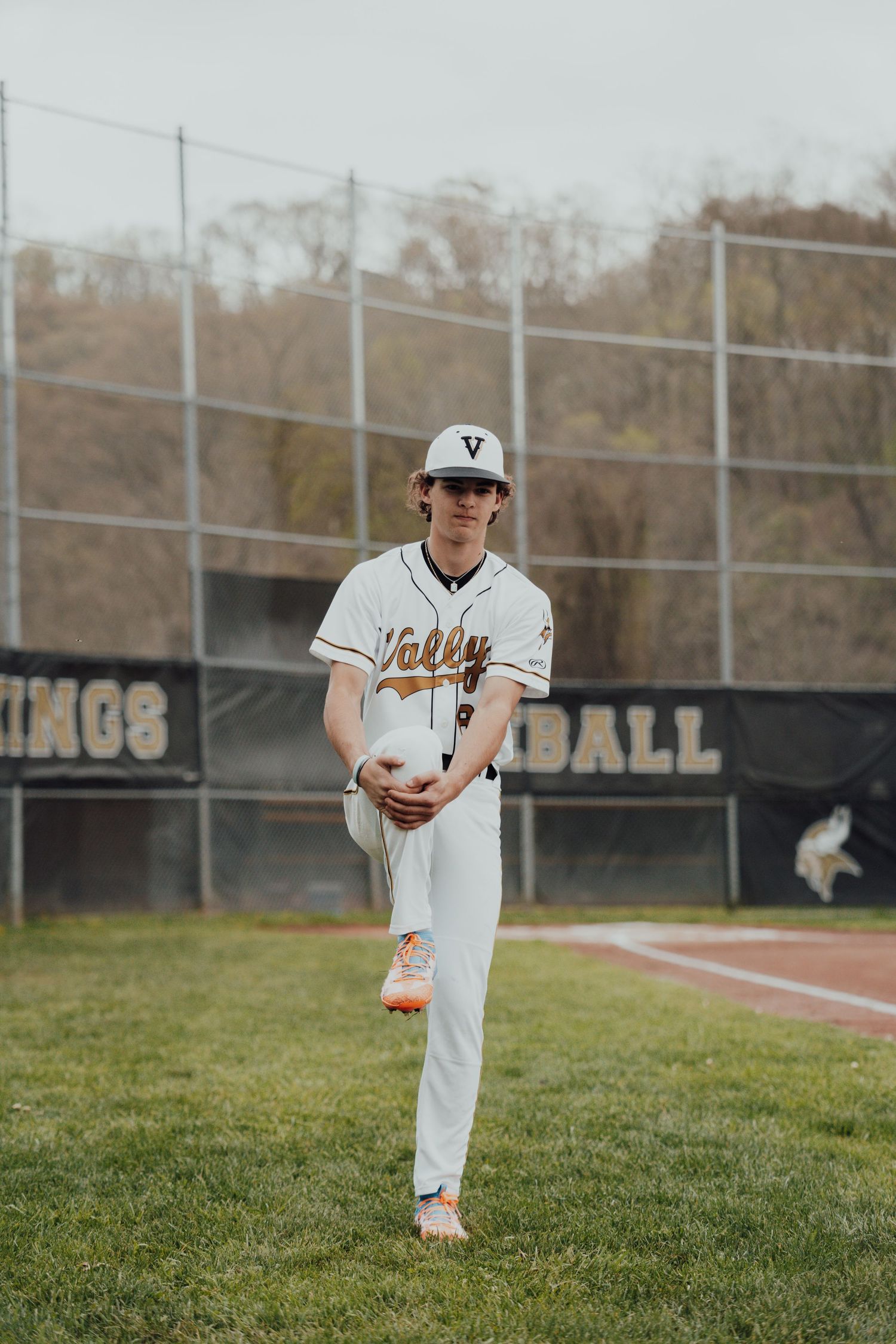 Baseball player in white uniform and cap running on grassy infield.