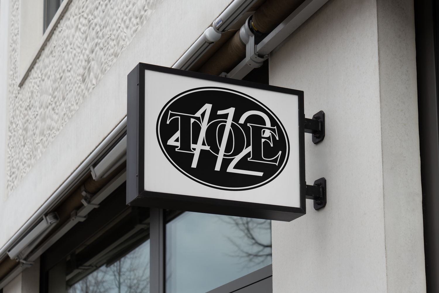 A row of illuminated storefront signs and awnings on a white building facade at night.