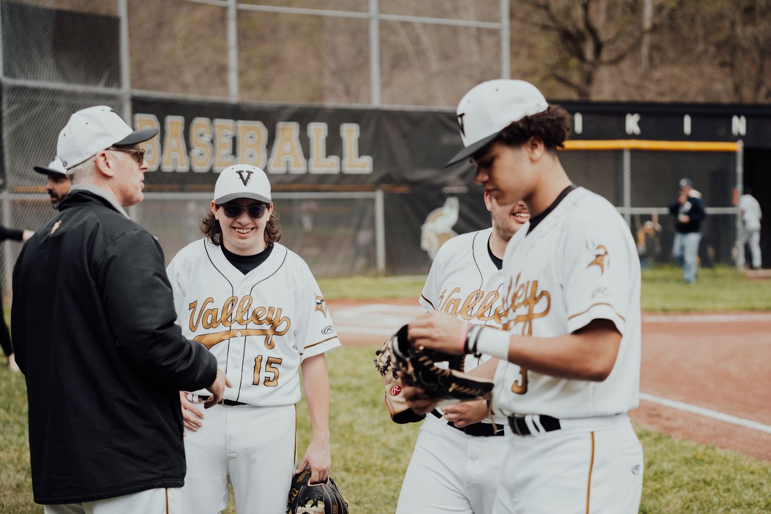 Baseball players and coach gather for a discussion during practice on the field.