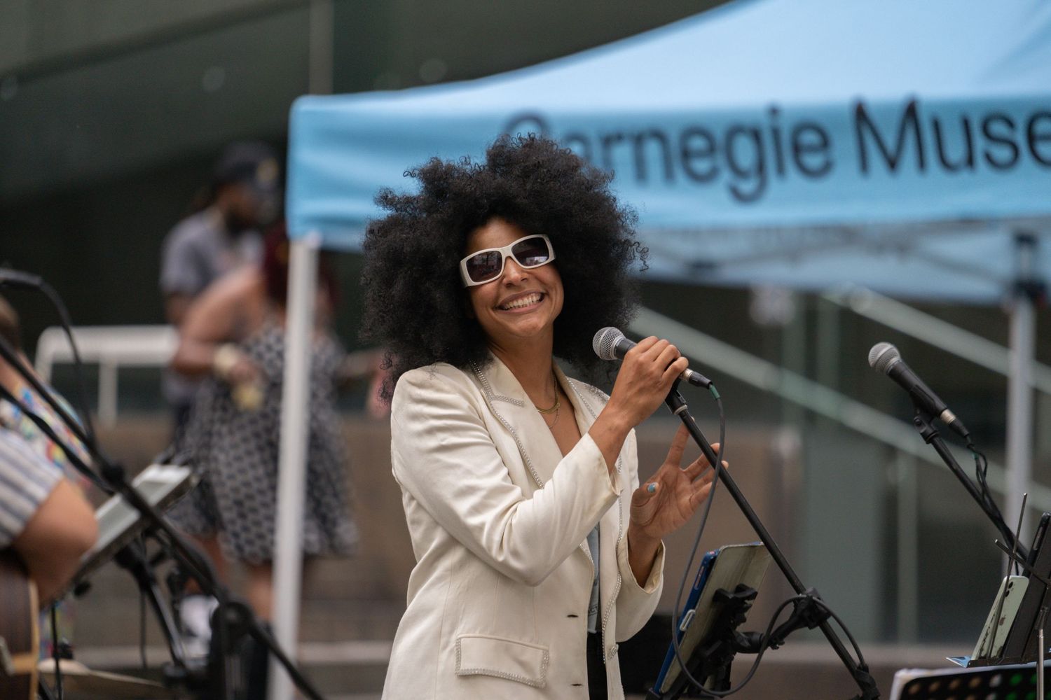 Outdoor performance at Carnegie Museum with musicians on stage in bright daylight.