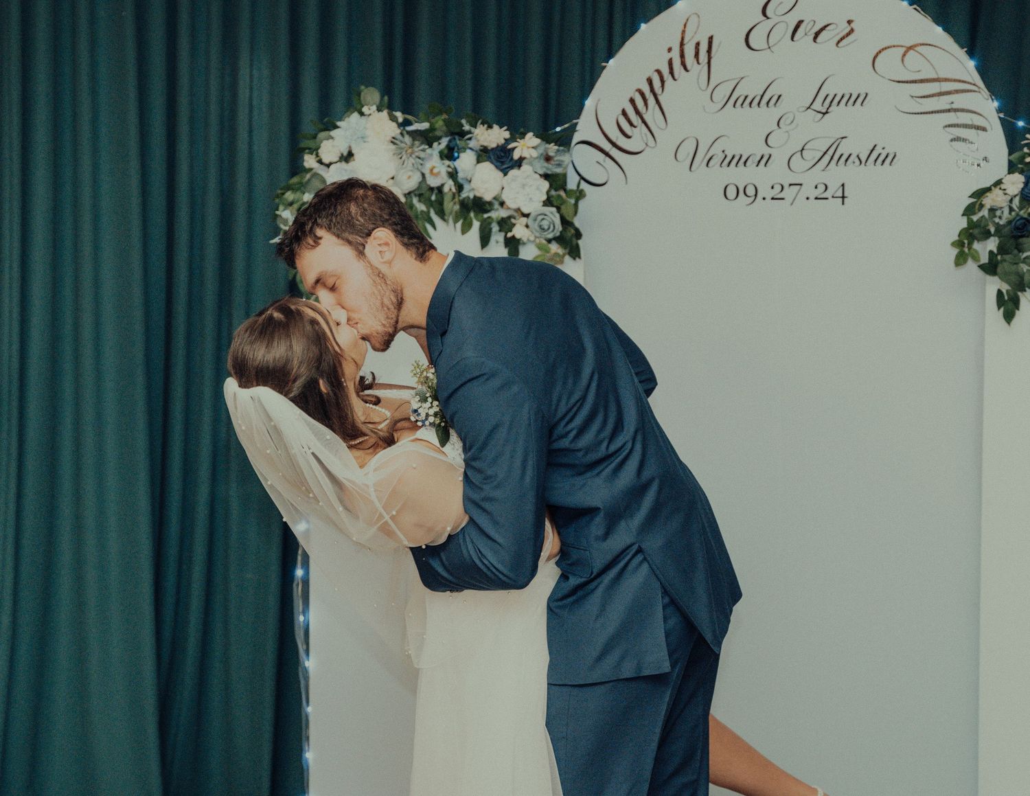 A wedding ceremony backdrop with elegant text and floral decorations.