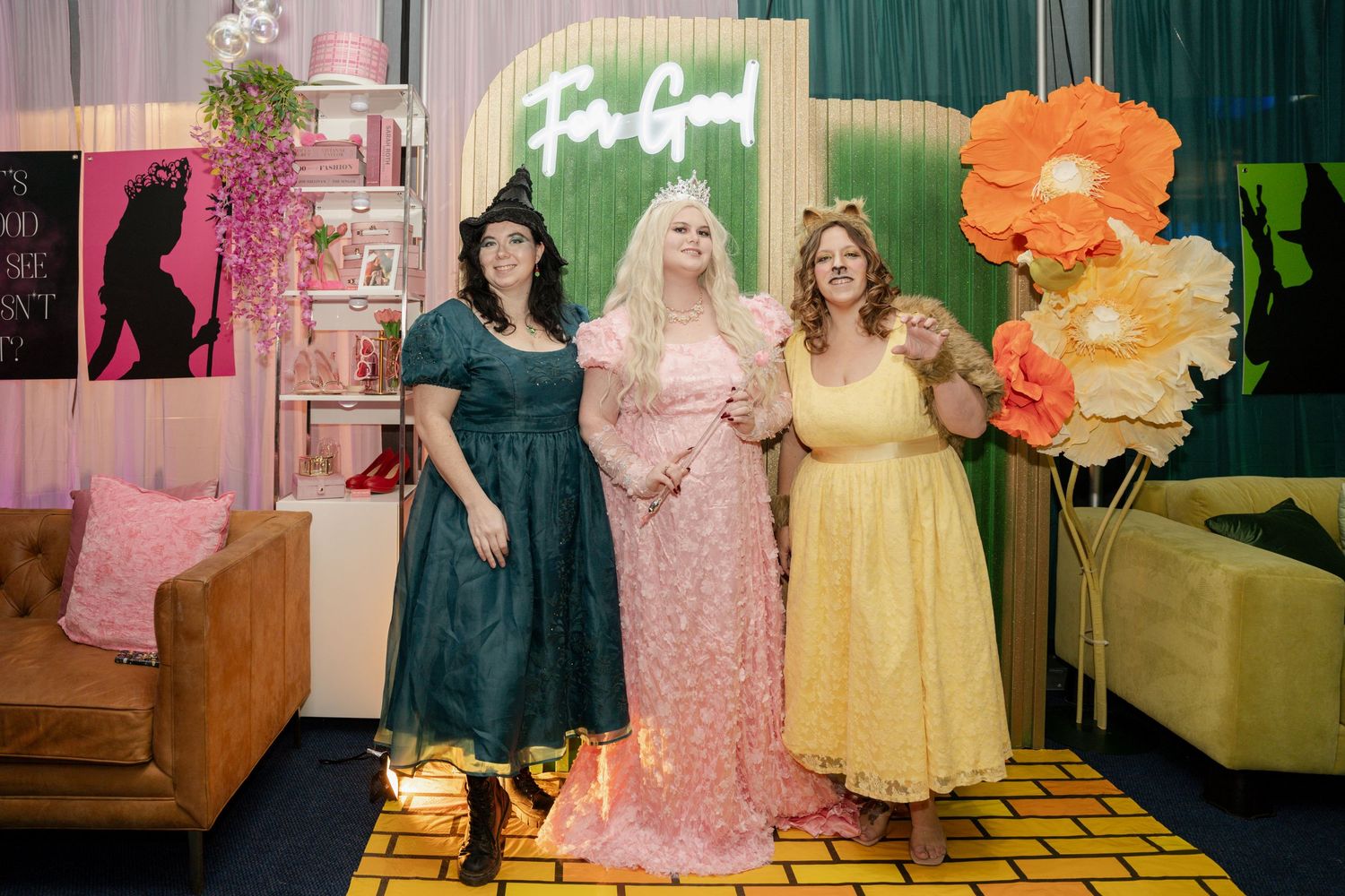 Group pose in colorful dresses against floral backdrop at formal event.