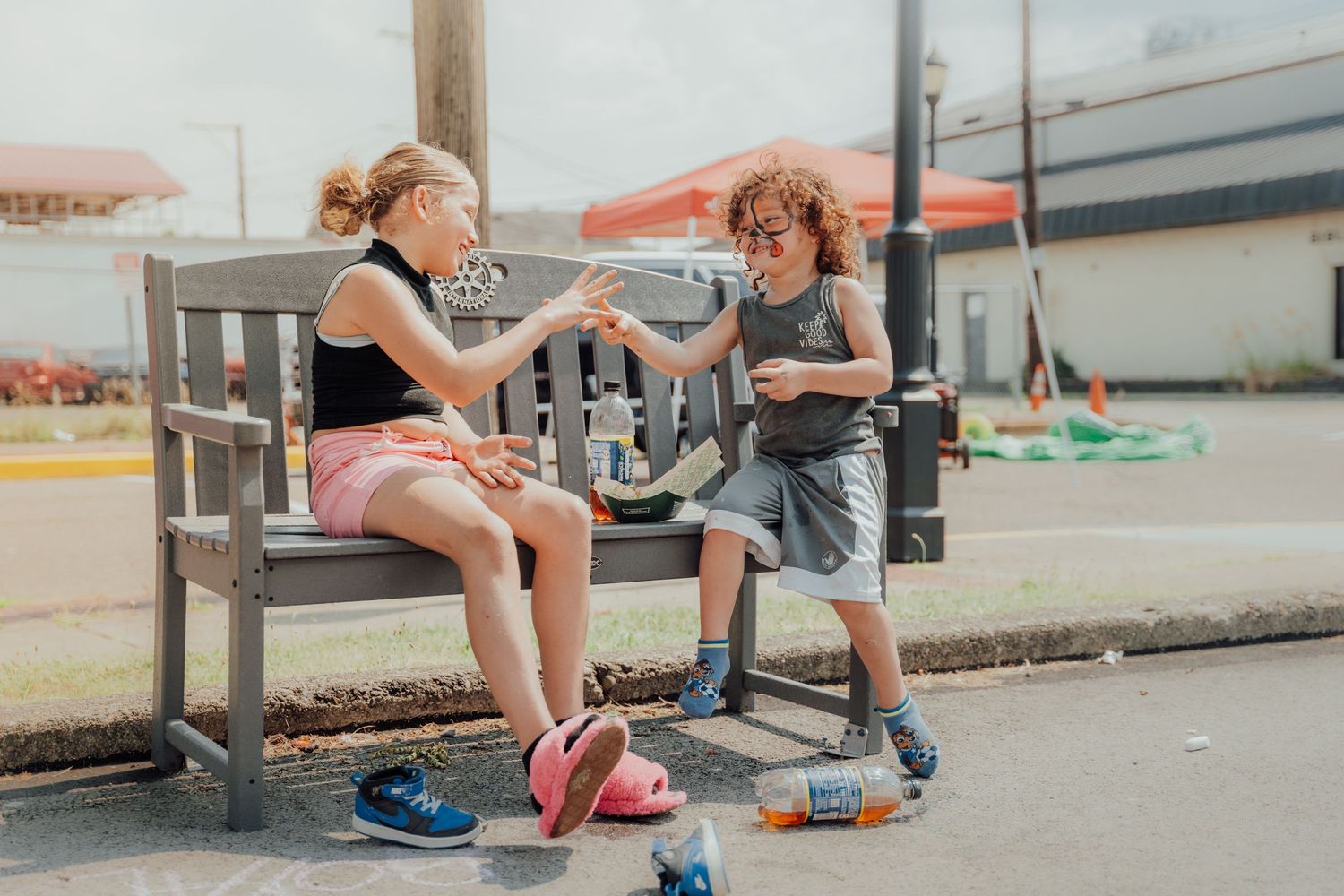 Group of kids sitting together and chatting on outdoor steps with sneakers and casual attire.