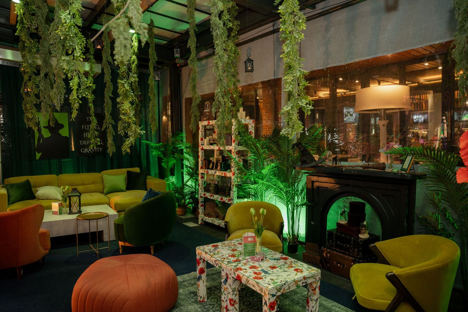 Modern lounge area decorated with hanging greenery, colorful furniture, and ambient lighting.