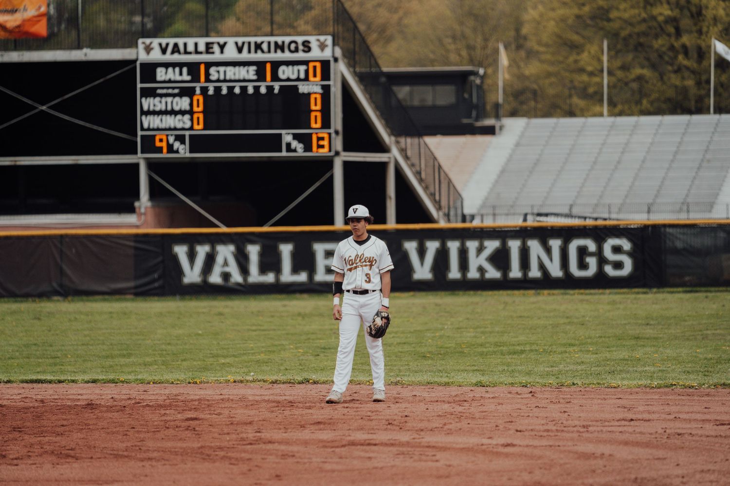 Baseball field with Valley Vikings scoreboard visible in background during daytime game.