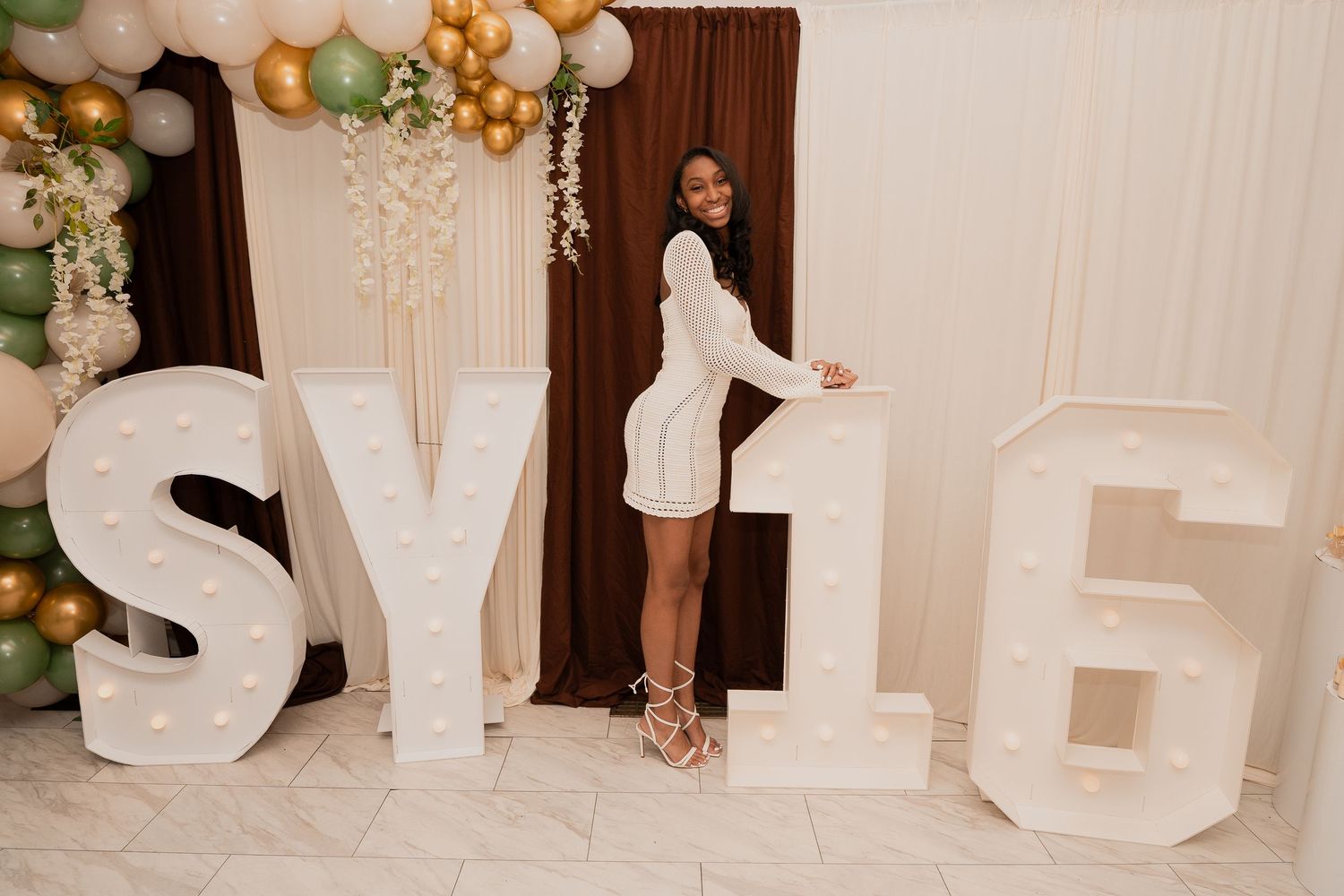 A celebratory setup with large white decorative letters and balloon arrangements.