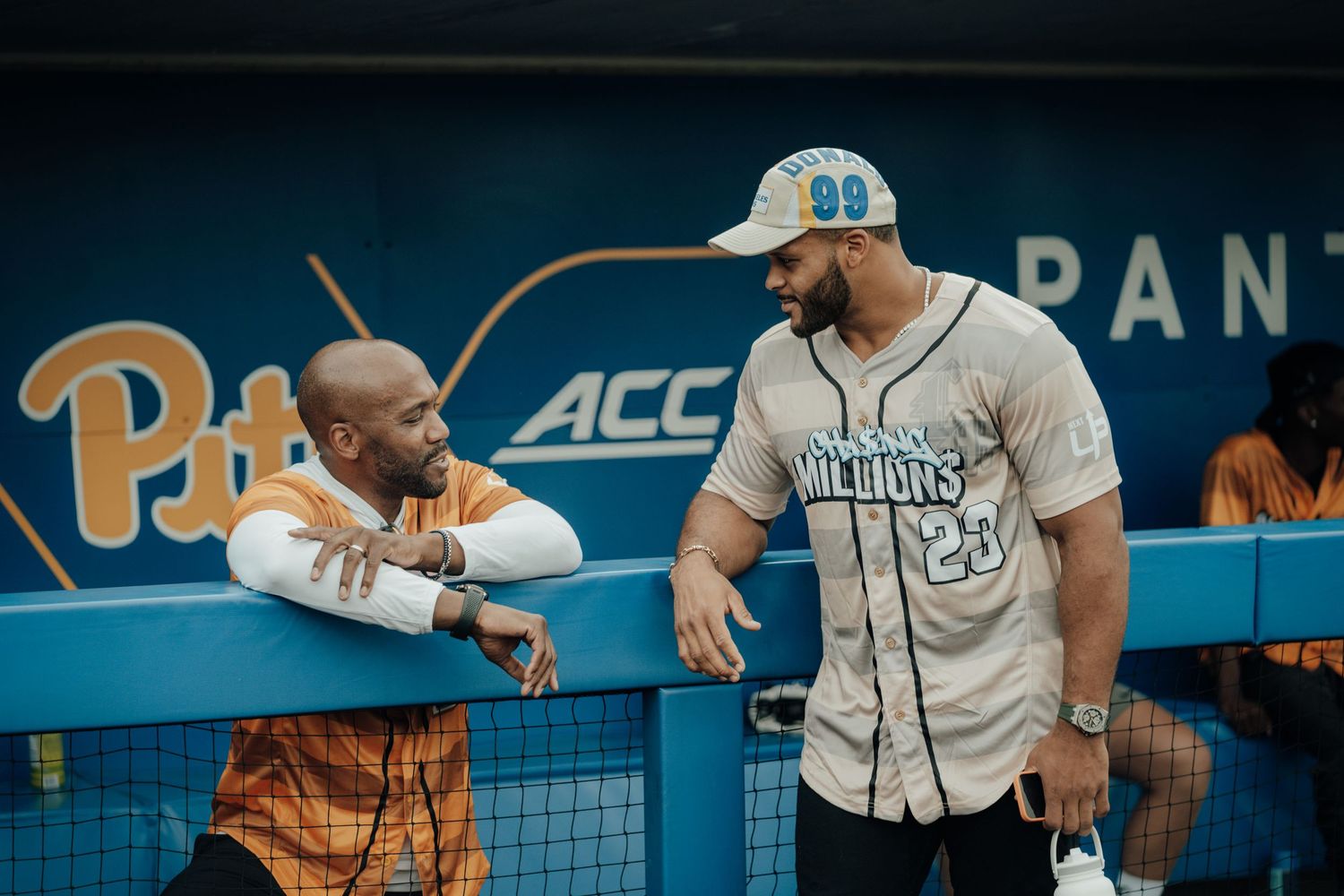 Two people in baseball uniforms having an animated conversation in the dugout at an ACC baseball game.