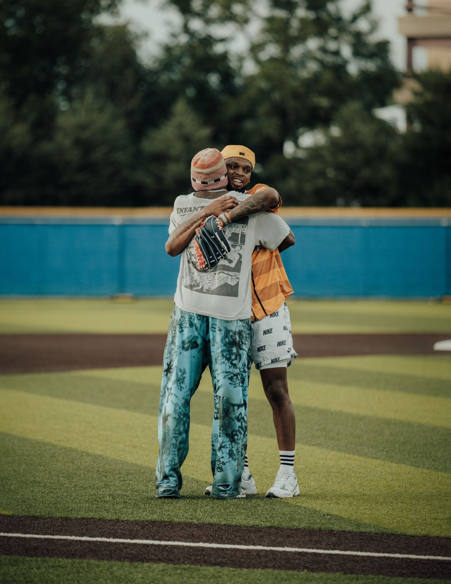 Two players in matching uniforms display inspiring sportsmanship with a supportive embrace on the baseball field.