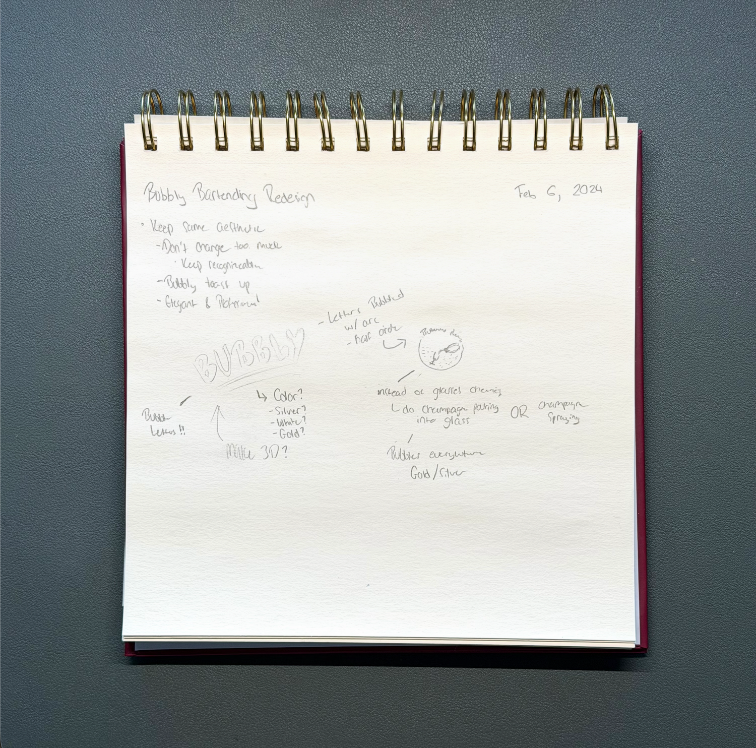 Spiral-bound notebook pages with handwritten notes on a dark gray surface.