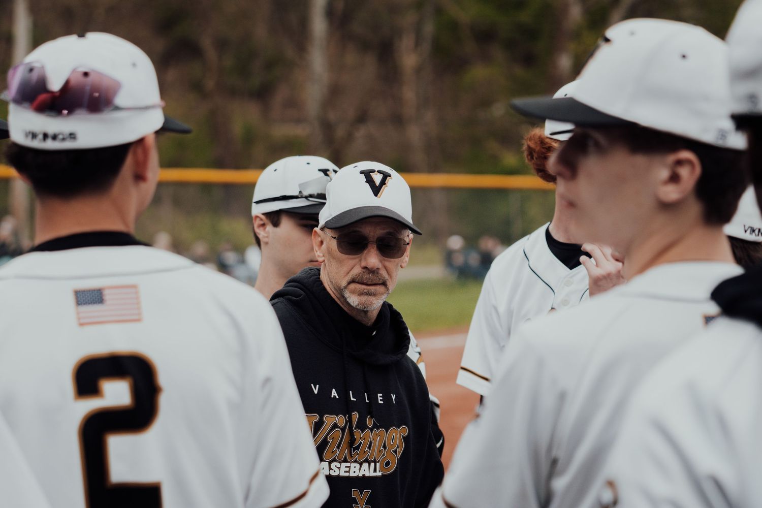 Baseball team huddles with coach for strategy discussion during game.