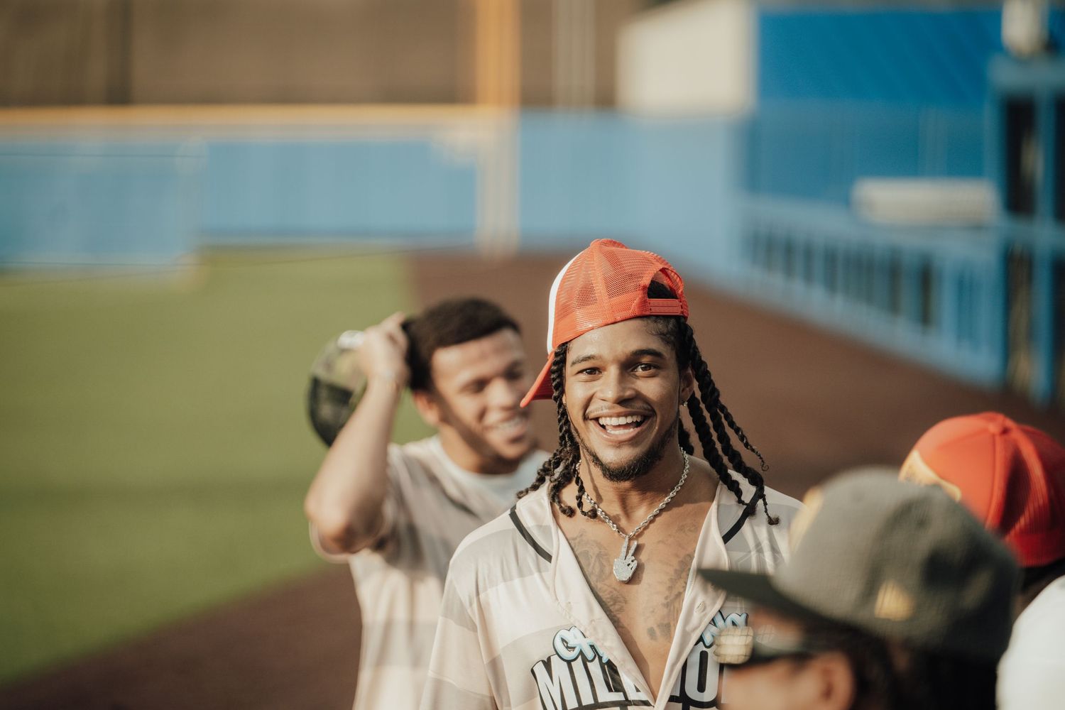Group of baseball players sharing a lighthearted moment together in the dugout at a sports field.