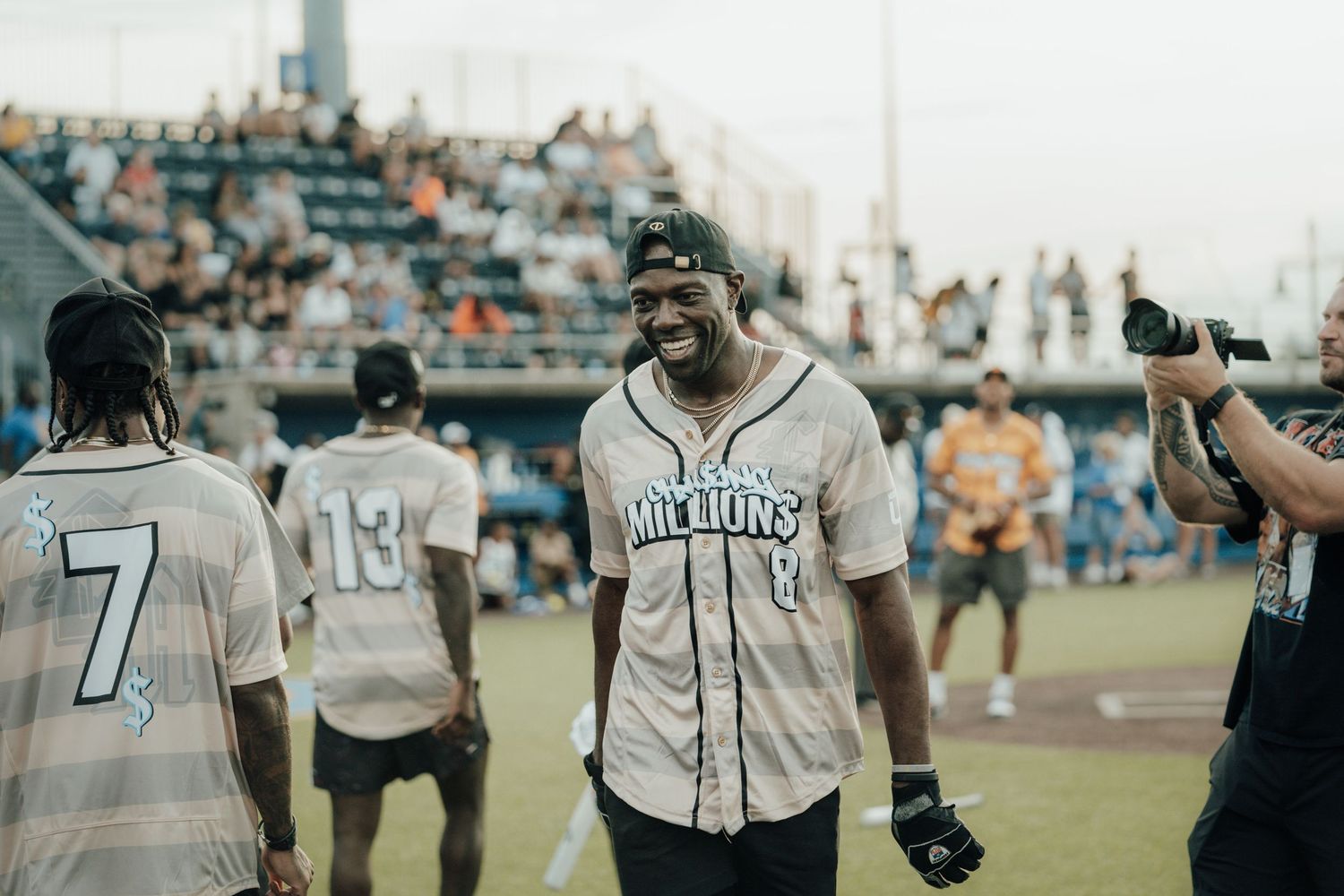 Baseball players in vintage-style jerseys gather on a field during a throwback or historical recreation game.