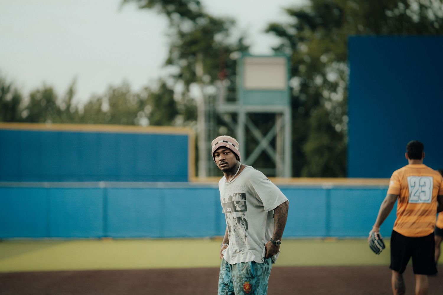 Baseball players warming up on field before a game at a community baseball stadium.