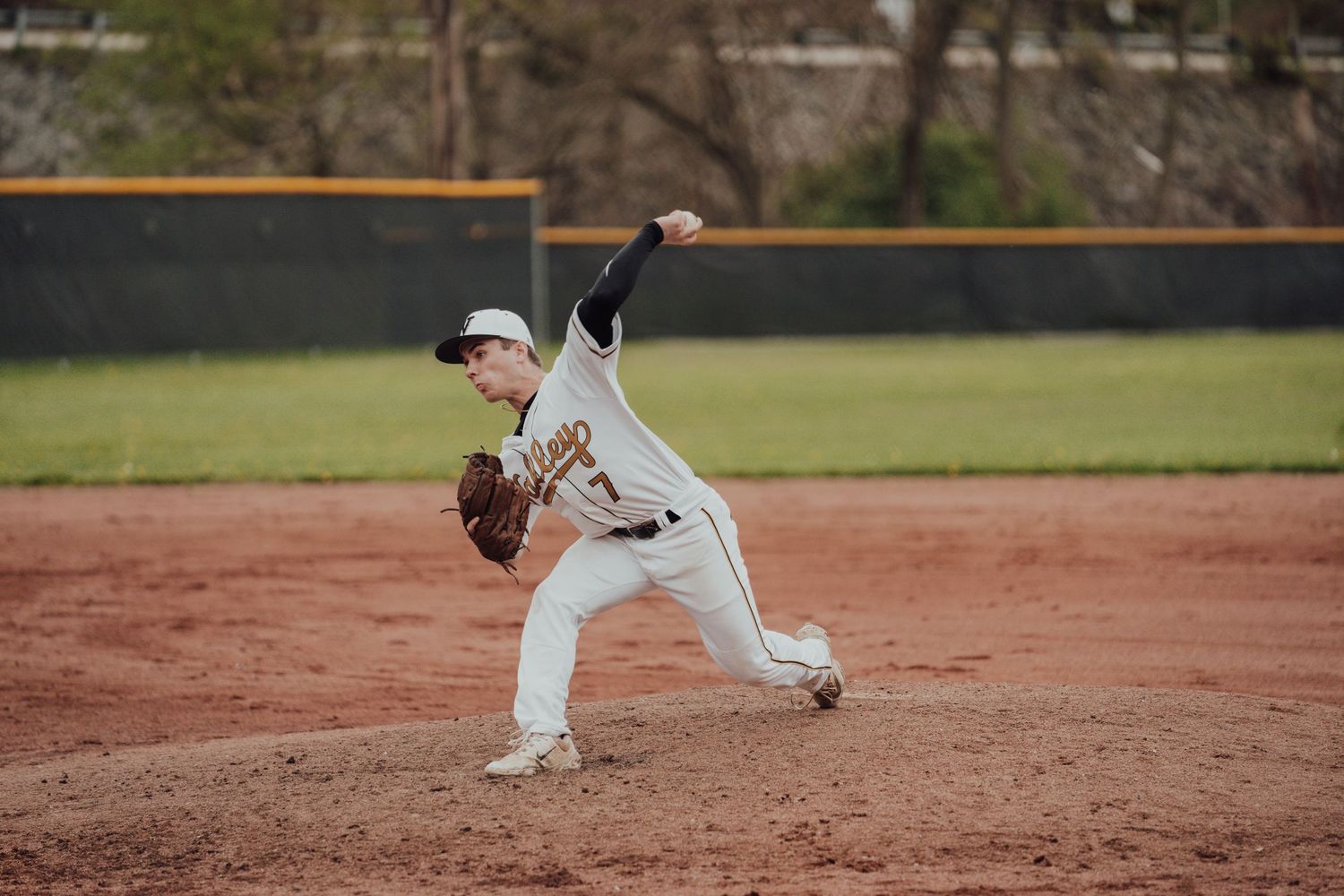 Baseball players practicing fielding drills on a dirt infield during training.