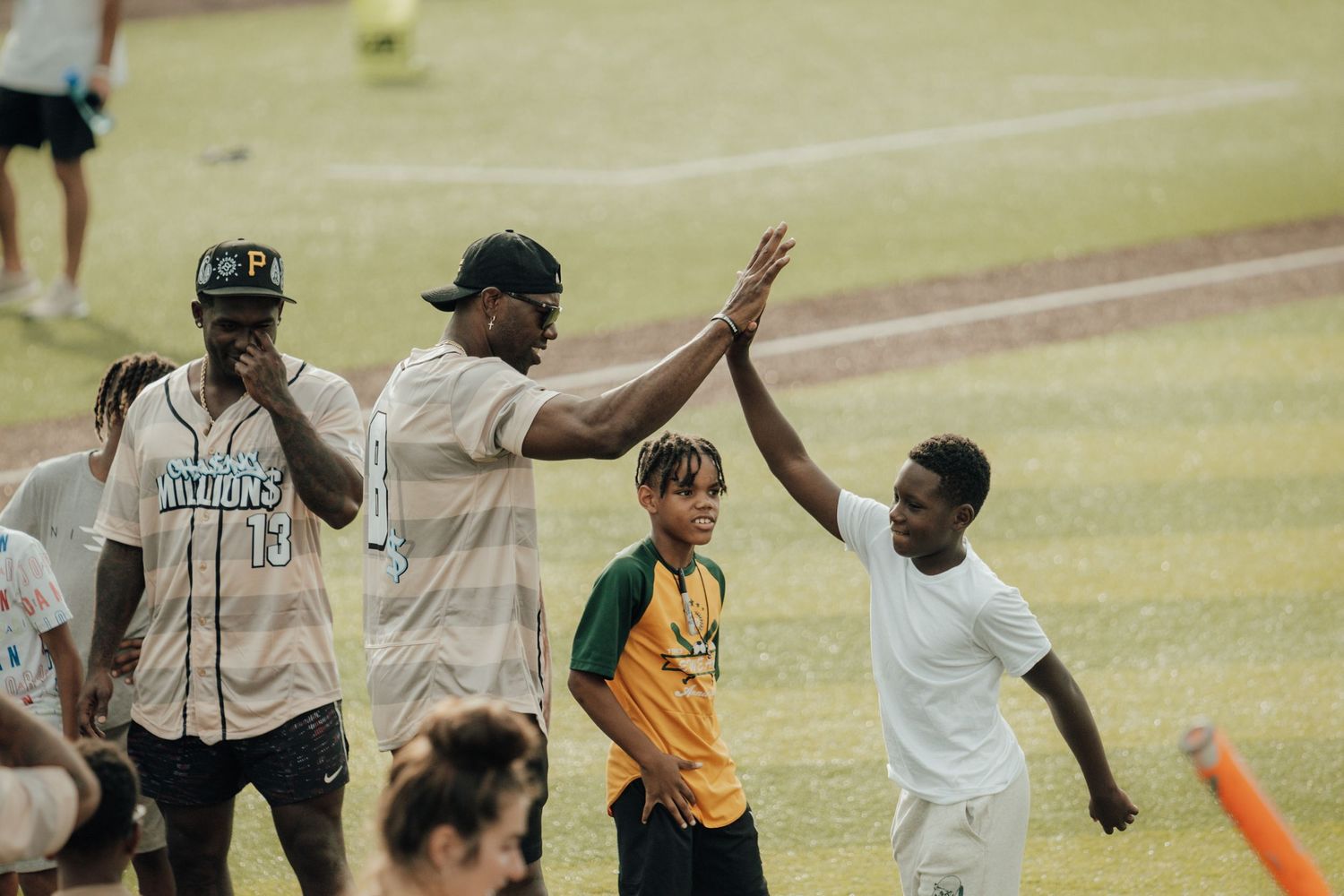 Baseball players celebrate on the field with high fives while wearing jerseys in different team colors during a game.