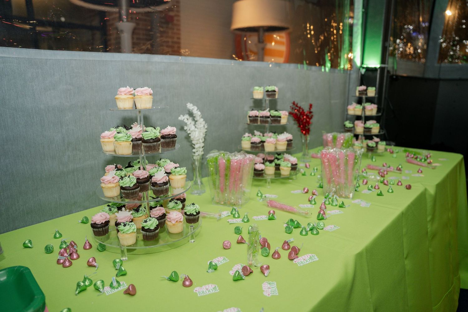Long banquet table displaying cupcakes and desserts on a lime green tablecloth.