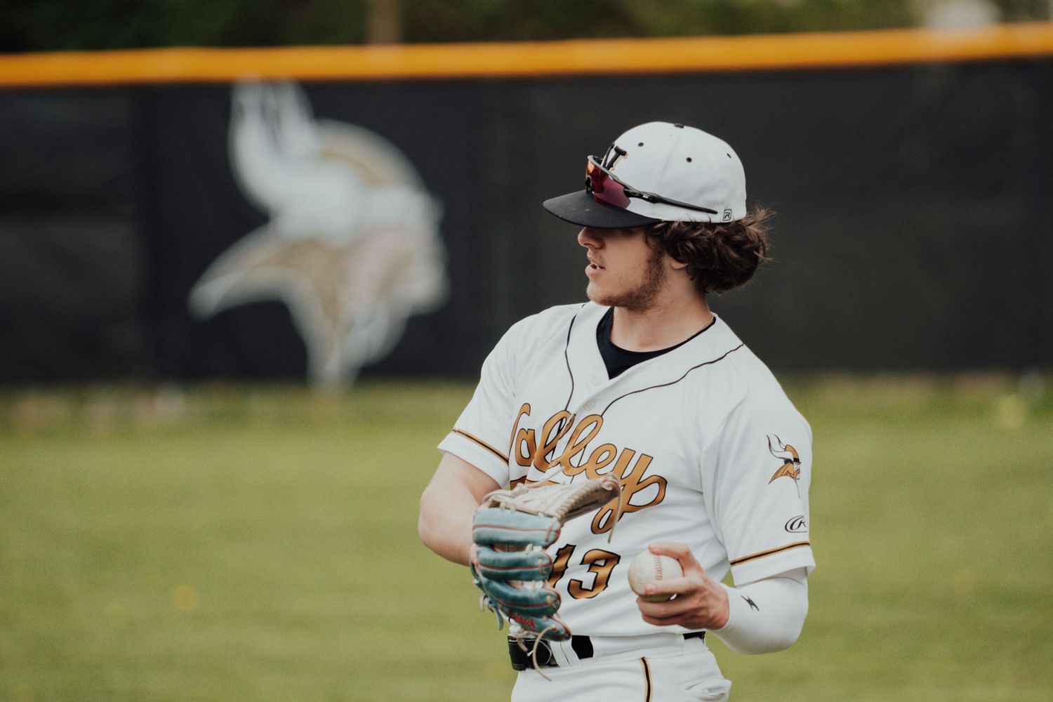 Baseball player in white uniform stands ready in fielding position.