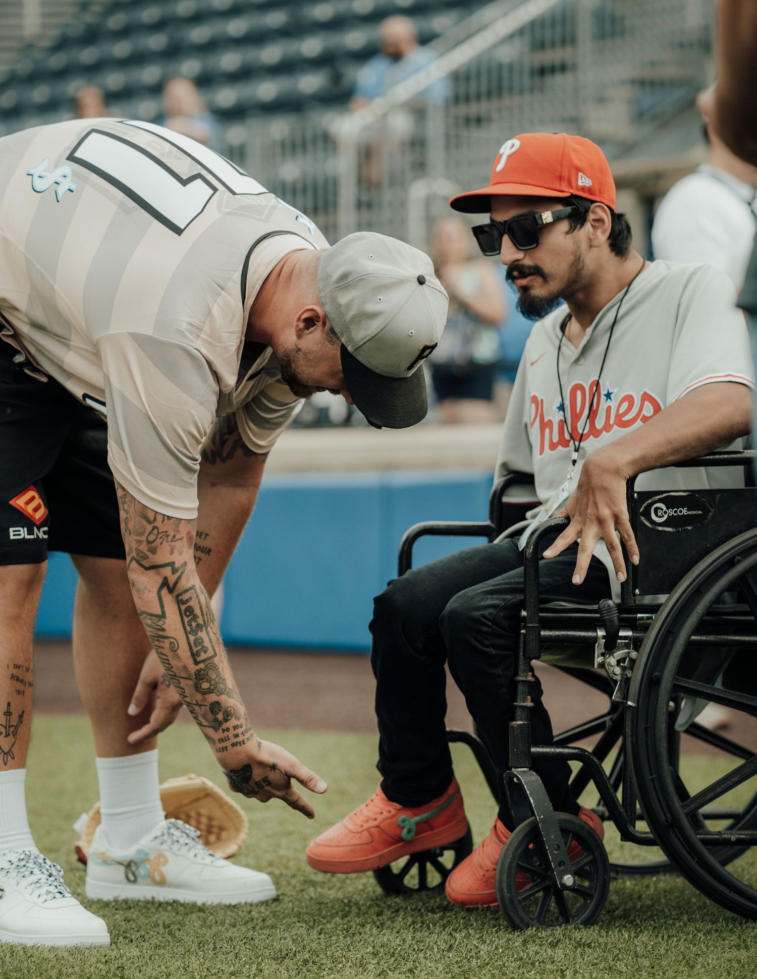 A parallel series of wheelchair athletes adjusting their shoes and equipment on a grass field before a sporting event.