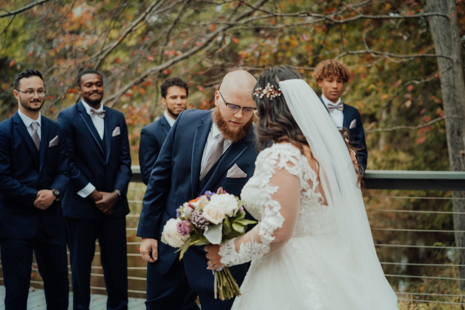 Wedding ceremony with groomsmen watching couple during fall outdoor celebration.