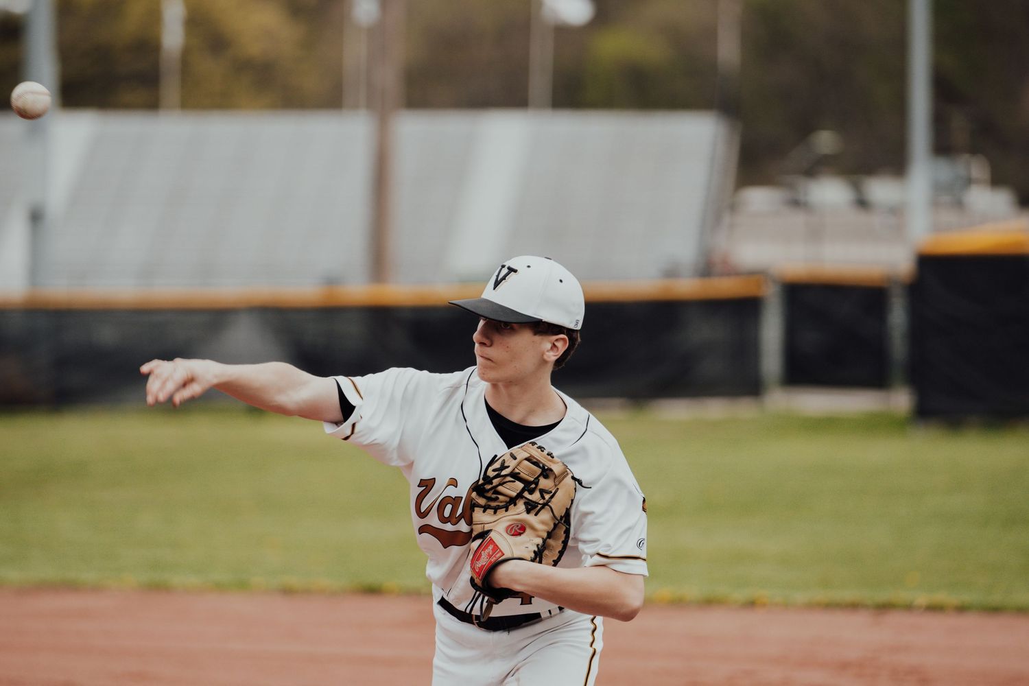 Young baseball players in white uniforms practicing pitching motions on a sunny field.