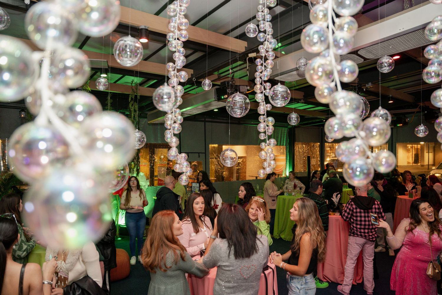 Festive party scene with hanging bubble decorations and guests mingling under sparkly lighting.